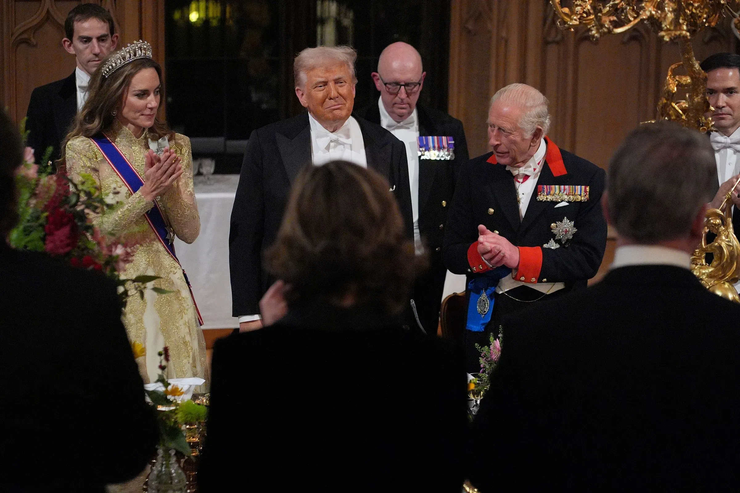 ترامب يتوسط الملك تشارلز الثالث وكاثرين، أميرة ويلز، في مأدبة رسمية، مع أجواء ملكية فاخرة تعكس أهمية الزيارة.