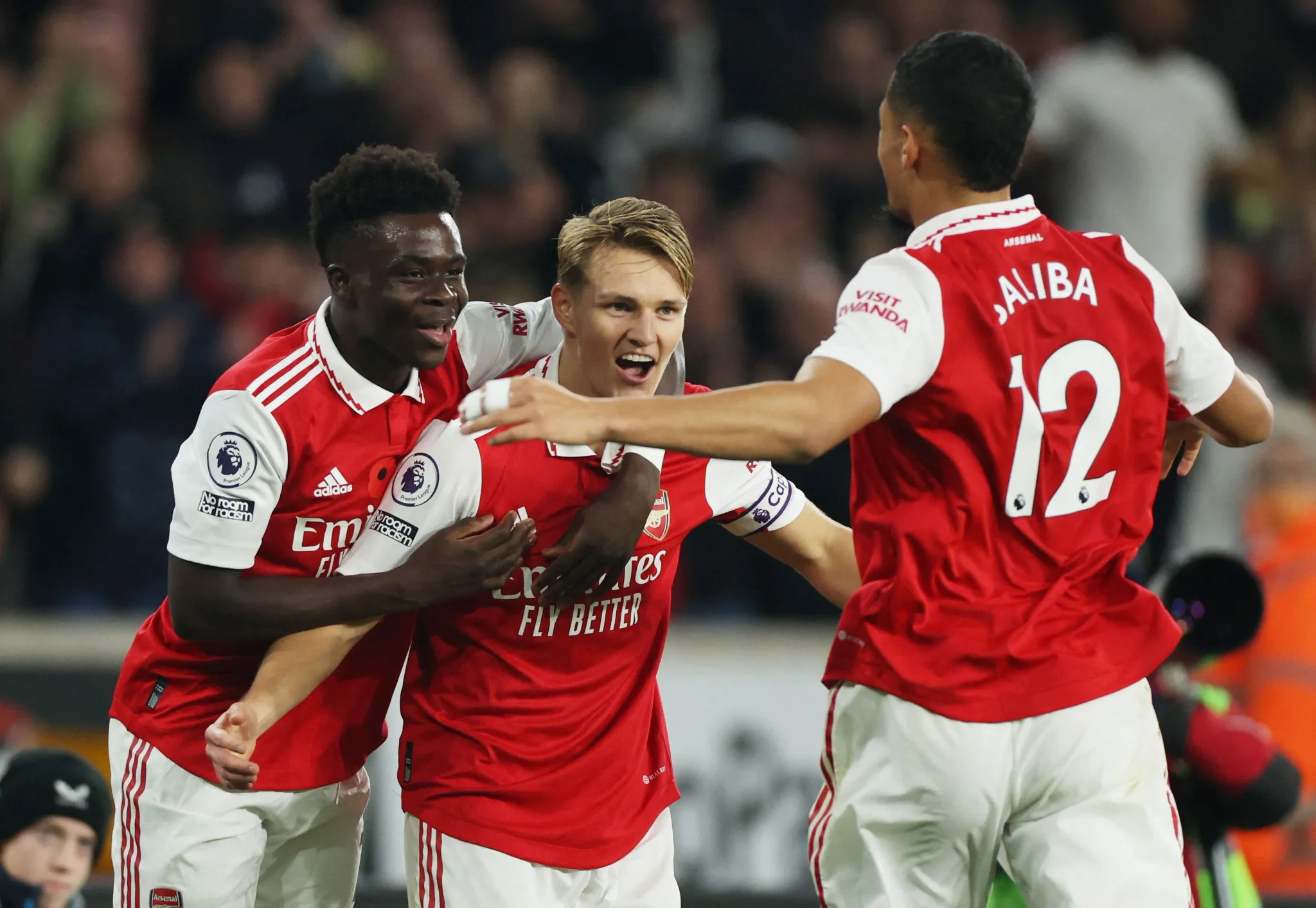 فرحة لاعبي Arsenal بعد تسجيل هدف، حيث يحتفل Bukayo Saka وMartin Ødegaard مع زملائهم في الفريق، مع أجواء حماسية في الملعب.