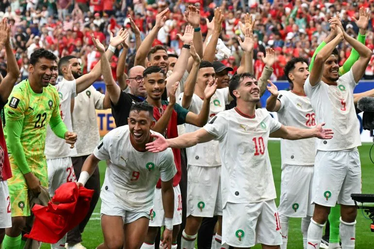 لاعبو المنتخب المغربي لكرة القدم يحتفلون بفوزهم في مباراة ضمن بطولة كأس العالم 2026، مع تعبيرات فرح واضحة وأجواء حماسية.