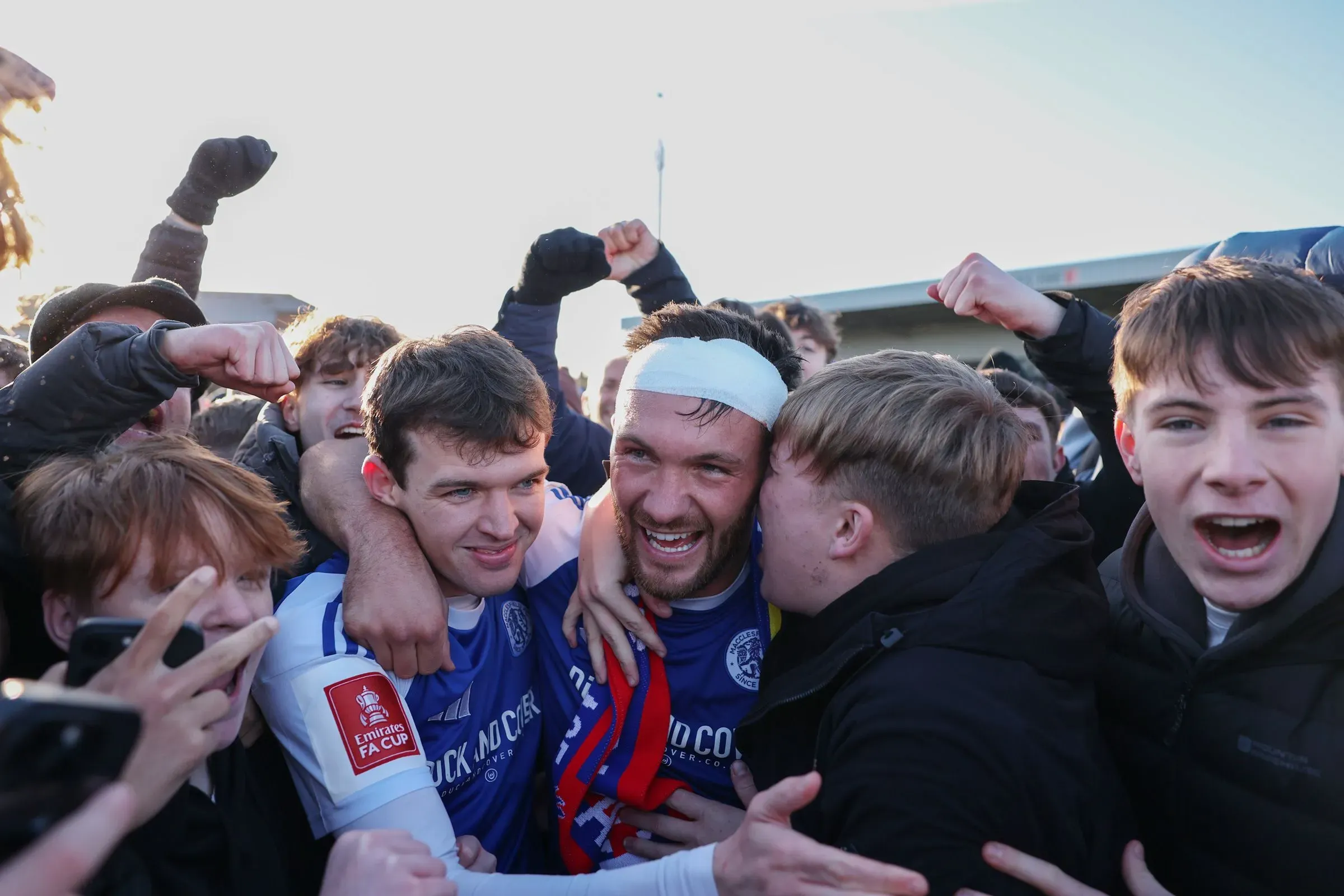 احتفال حماسي للاعبي ماكلسفيلد مع الجماهير بعد فوزهم المفاجئ على كريستال بالاس في كأس الاتحاد الإنجليزي، مع مشاعر الفرح والدهشة.