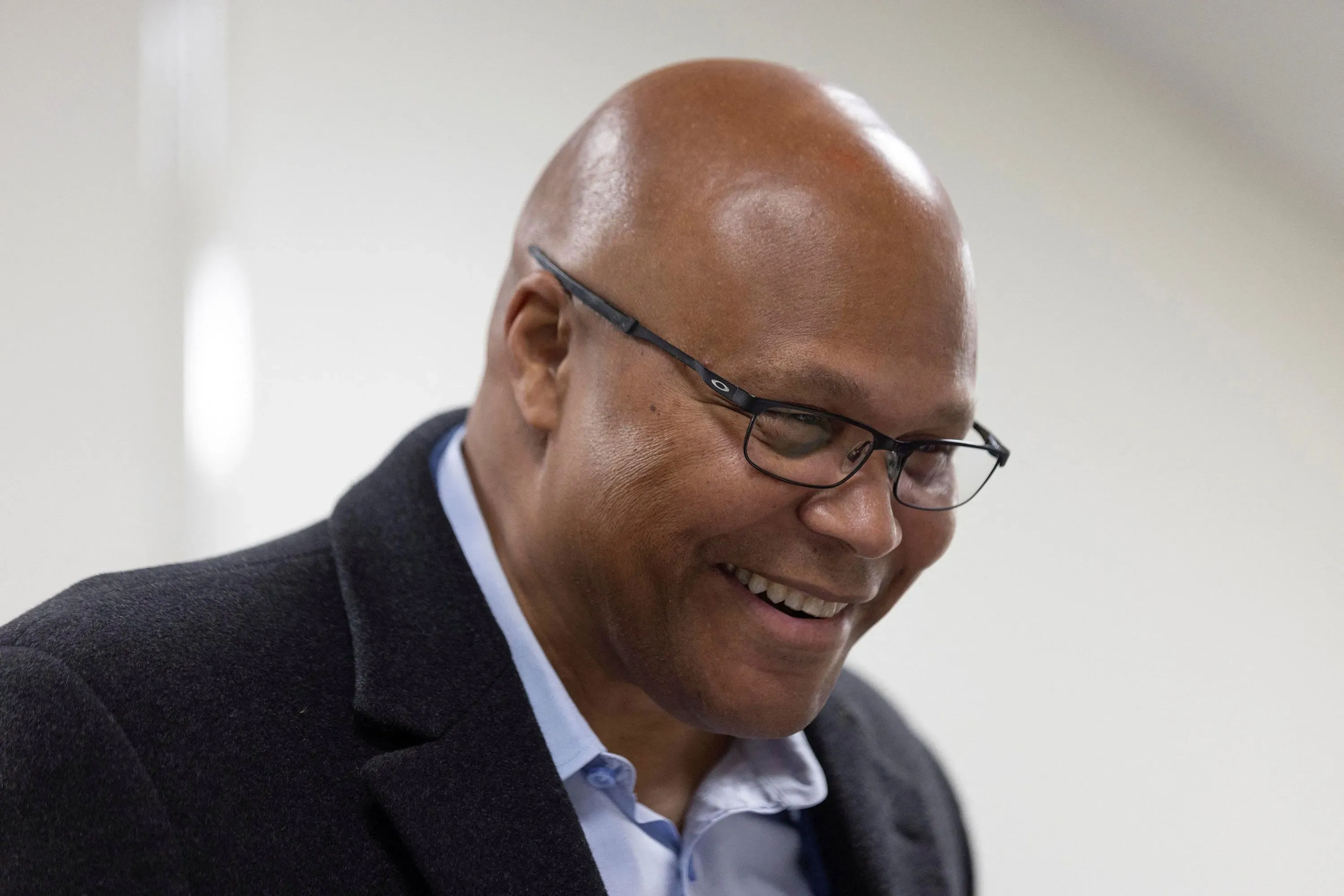 مرشح جمهوري مبتسم يرتدي نظارات وقميصًا أزرق تحت سترة داكنة، يظهر في حدث انتخابي في جورجيا، حيث يتنافس على مقعد في الكونغرس.