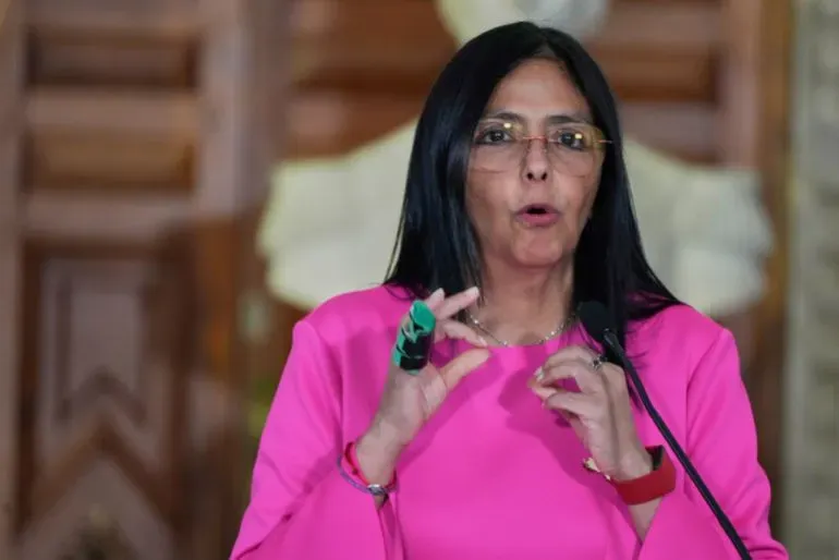 امرأة ترتدي قميصًا ورديًا، تتحدث في مؤتمر صحفي، تعبر عن موقفها بشأن الأحداث السياسية في فنزويلا بعد اختطاف مادورو.