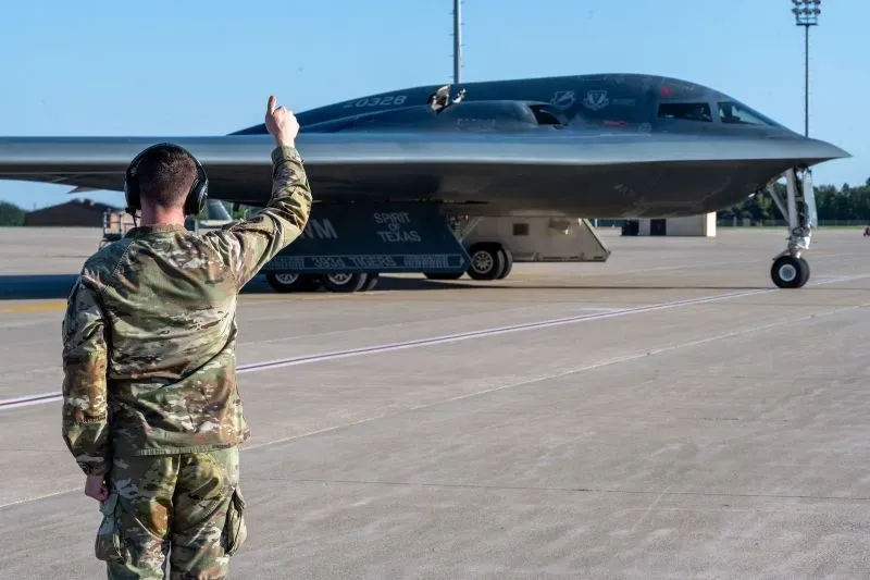 ضابط عسكري يوجه قاذفة B-2 الأمريكية على مدرج الطائرات، مشيرًا إلى التحديات الأمنية التي تواجه الطائرات الحربية.
