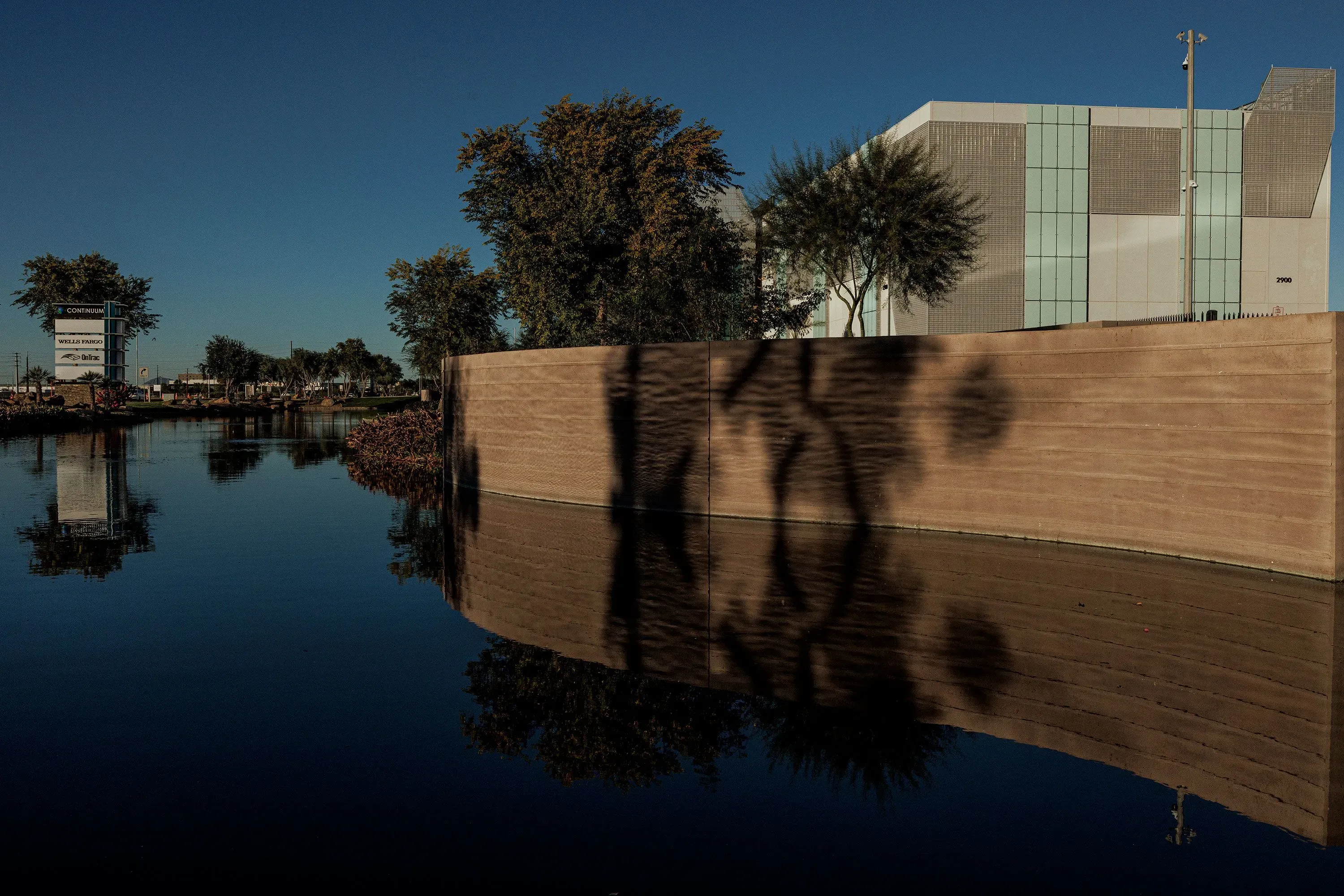 مشهد لمركز بيانات حديث في تشاندلر، أريزونا، يعكس في مياهه المحيطة، مع وجود أشجار على الجانبين، في سياق النقاش حول تأثيرات مراكز البيانات.