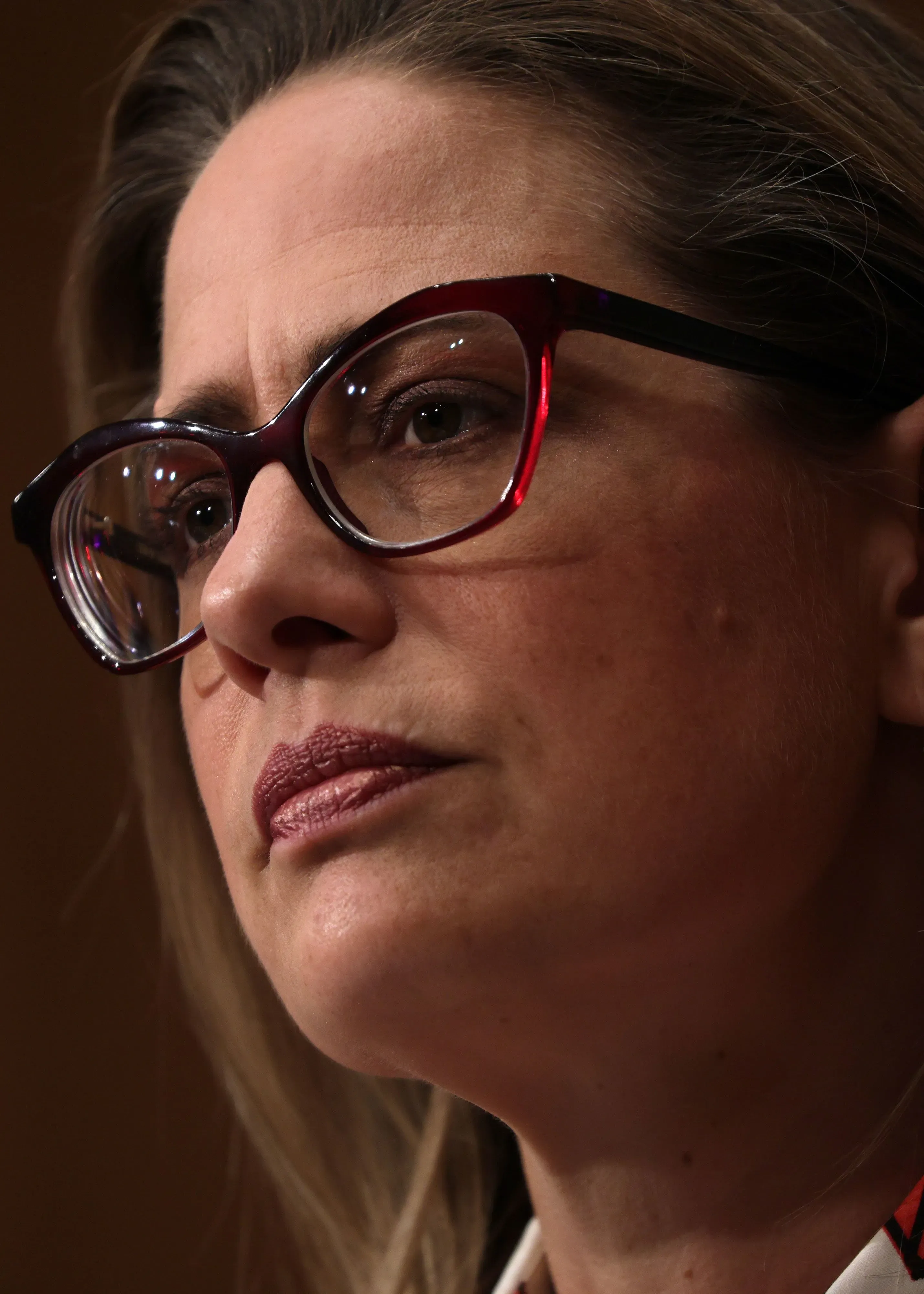 صورة قريبة لوجه كيرستن سينيما، السيناتور السابقة من أريزونا، تظهر تعبيرات جدية. تُبرز الصورة أهمية دورها في مناقشات مراكز البيانات.