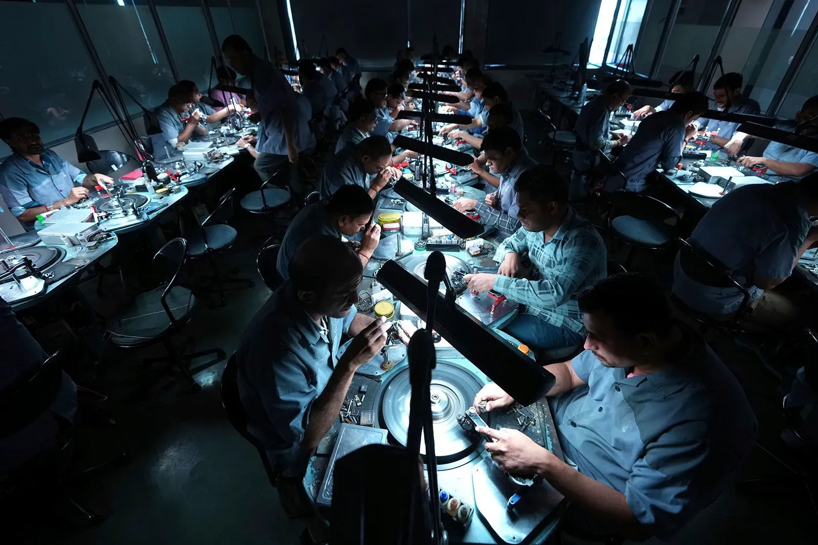 عمال في مصنع للملابس في تيروبور، الهند، يعملون على إنتاج الملابس وسط ظروف إضاءة خافتة، مما يعكس تحديات الصناعة.