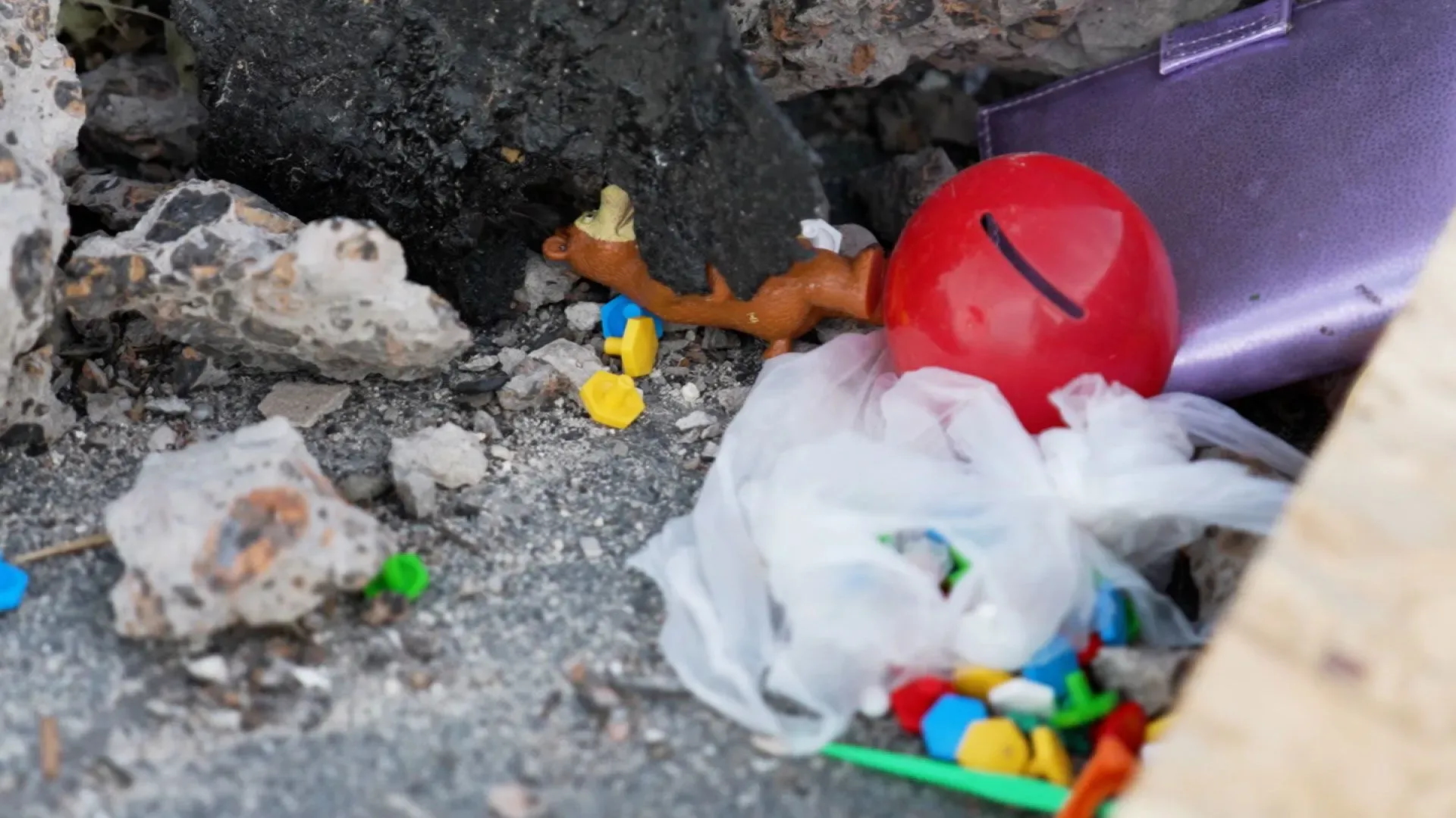 بقايا ألعاب ملونة، بما في ذلك كرة حمراء وقطع بلاستيكية، مكدسة بين الحطام، تعكس آثار الحرب على الأطفال في كراماتورسك.