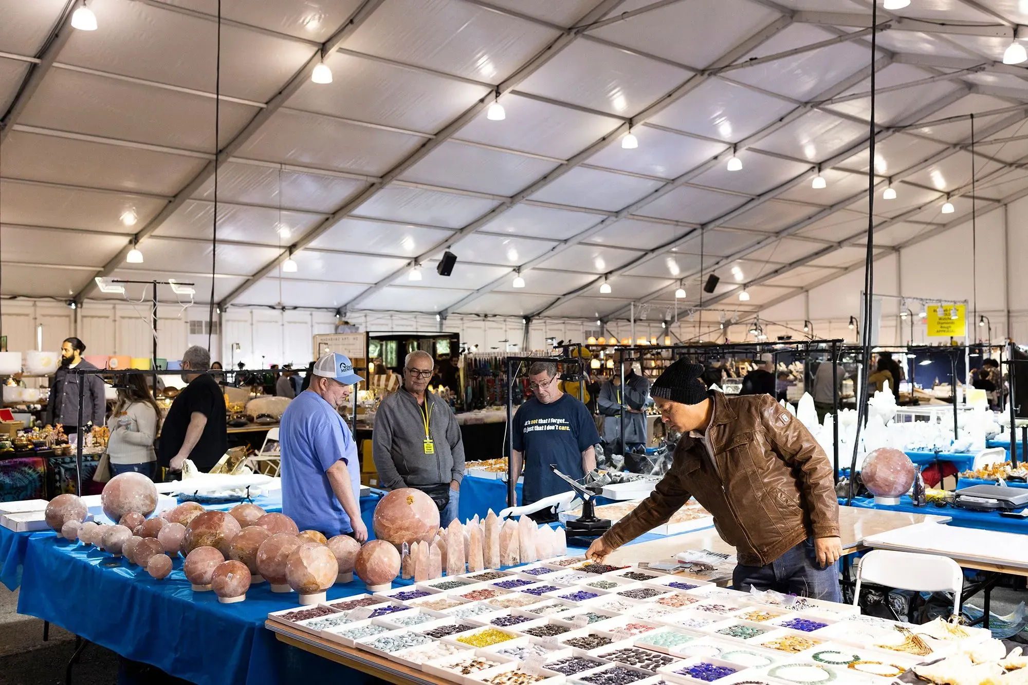 معرض لبيع الحفريات والآثار في خيمة كبيرة، حيث يتجول الزوار بين الطاولات المليئة بالعينات المتنوعة.