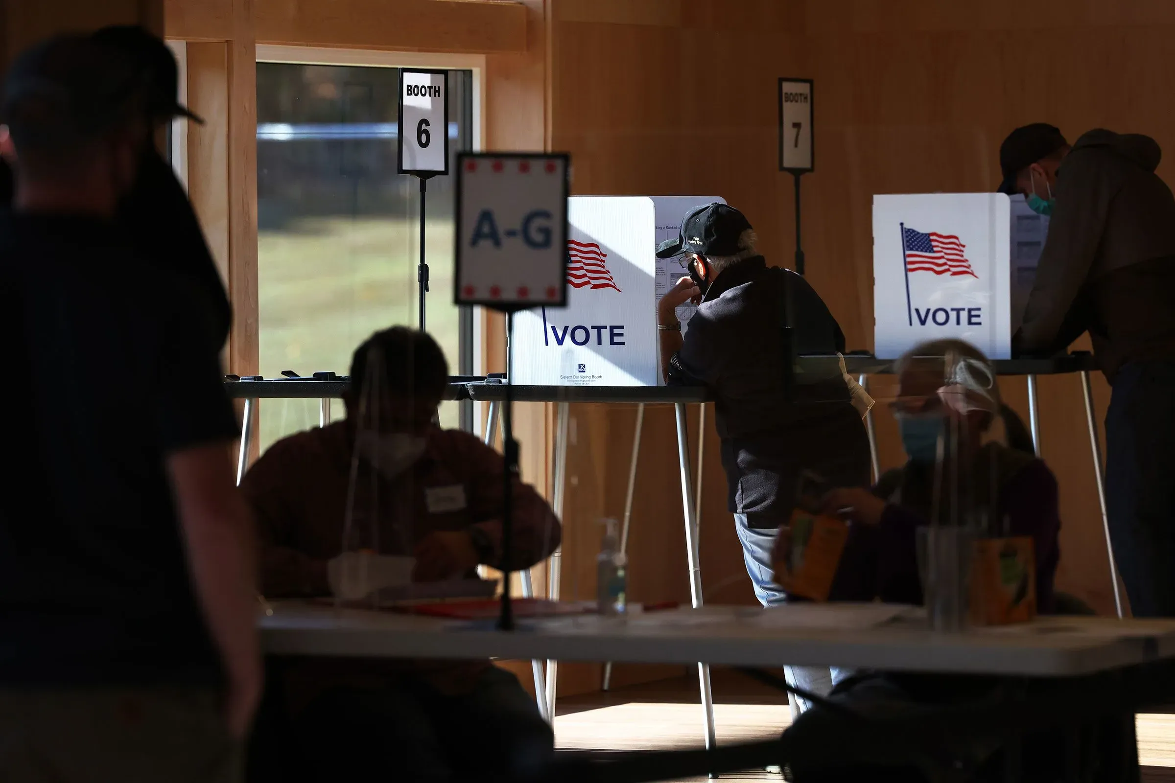 مواطنون يصوتون في مركز اقتراع، مع وجود صناديق اقتراع تحمل علم الولايات المتحدة، وسط مخاوف من تدخل قوات إنفاذ قوانين الهجرة والجمارك.