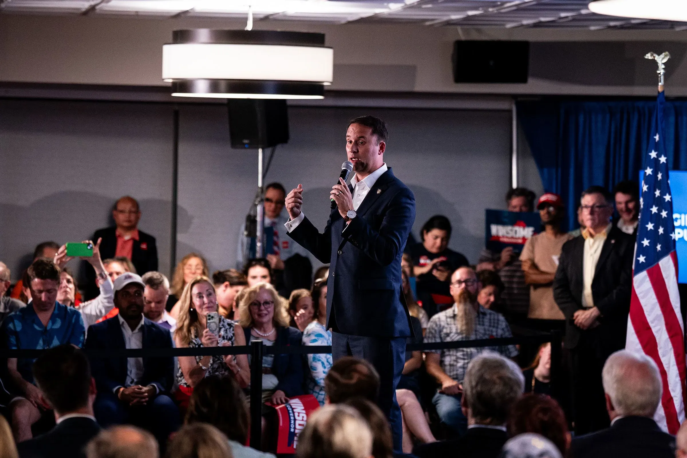 نائب الرئيس جيه دي فانس يتحدث في حدث سياسي، مع جمهور متنوع خلفه، حيث يدعو للمشاركة السياسية بعد وفاة تشارلي كيرك.