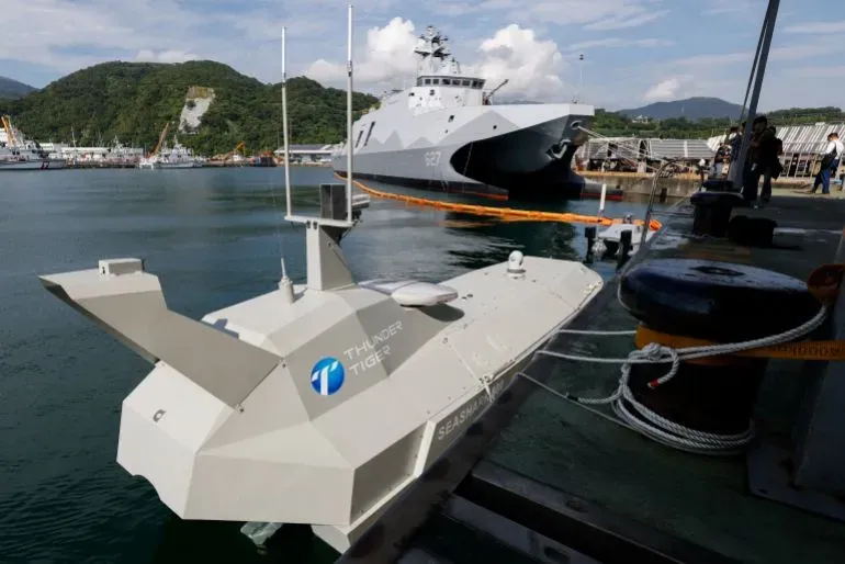 طائرة بحرية بدون طيار من طراز "سي شارك 800" بالقرب من قارب عسكري في ميناء تايواني، في إطار جهود تعزيز القوة البحرية.