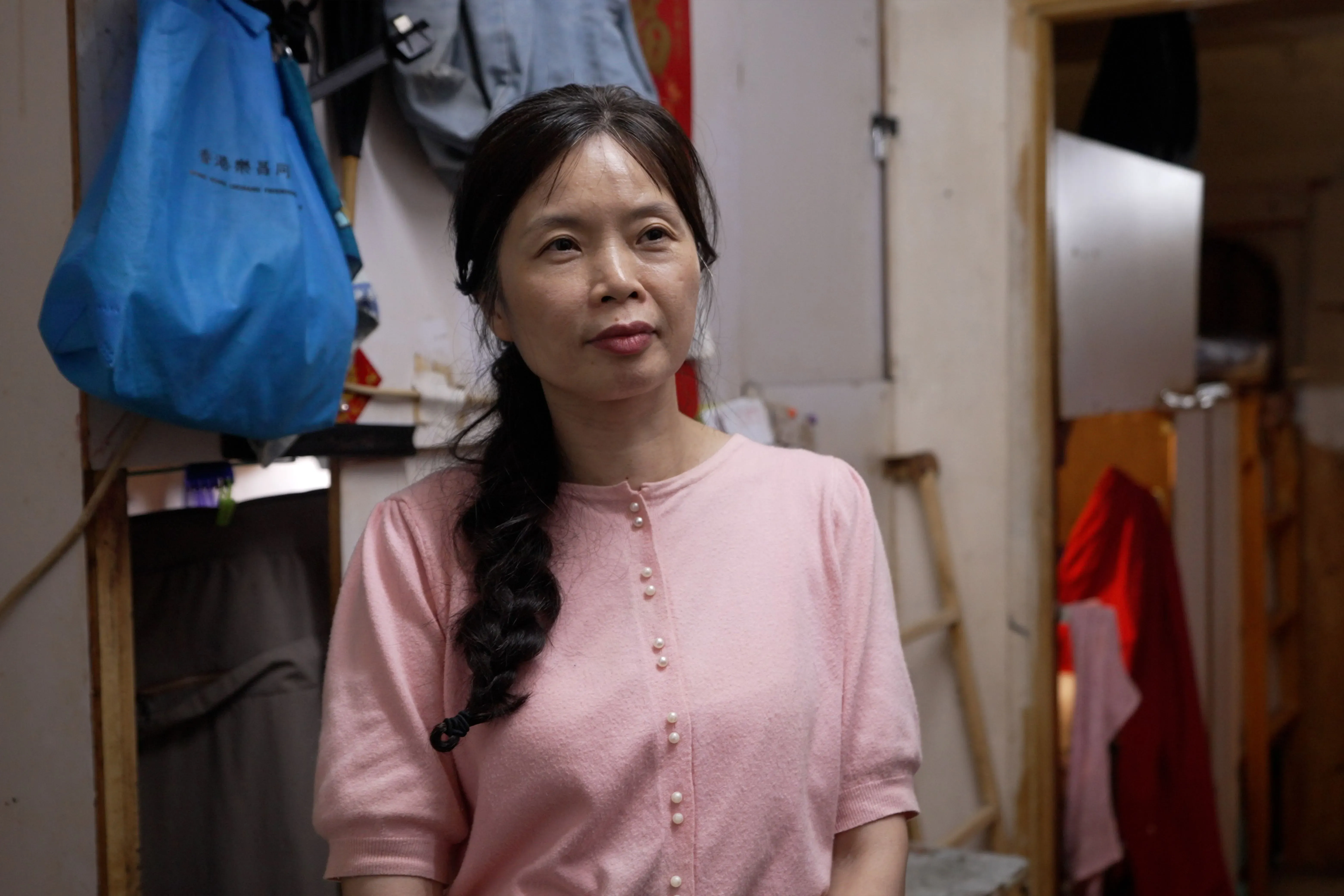 امرأة في شقة صغيرة في هونغ كونغ، تعاني من الحرارة الشديدة في ظروف معيشية غير لائقة، تعكس تأثير تغير المناخ على الفقراء.