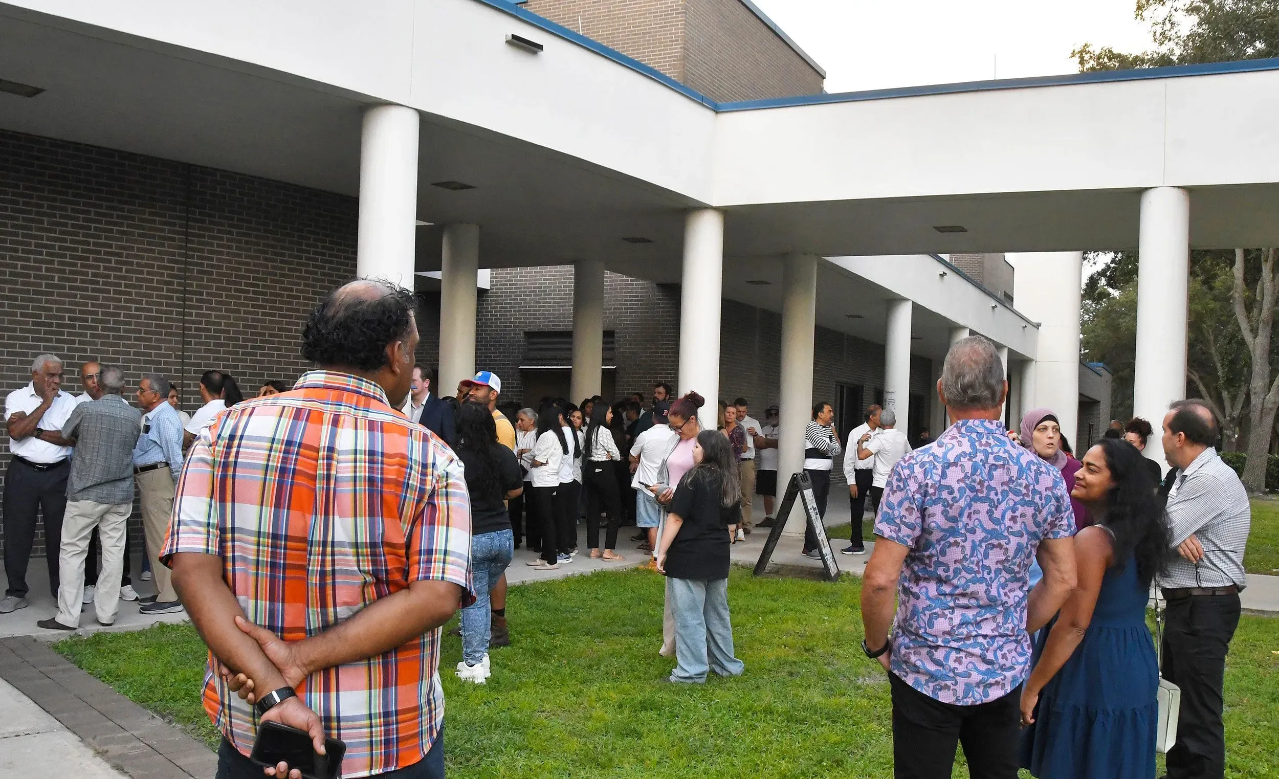 مجموعة من الأشخاص يتجمعون أمام مبنى، مع تعبيرات متنوعة، في سياق الاحتفالات بعيد ديوالي والتوترات السياسية في الولايات المتحدة.