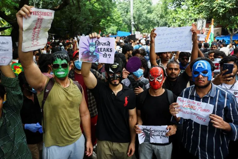 محتجون في نيودلهي يرتدون أقنعة شخصيات مشهورة ويطالبون باستقالة وزير التعليم خلال احتجاجات يوليو 2023 ضد فضائح تسريب الامتحانات.
