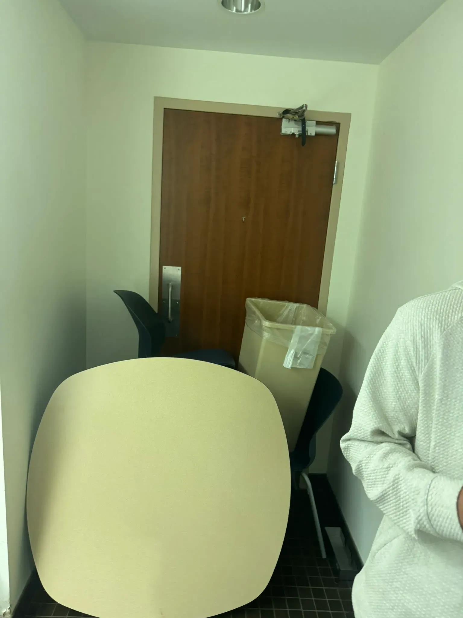 غرفة مغلقة في جامعة، حيث تم إغلاق الباب برفعة، مع وجود كراسي وصندوق قمامة، تعكس حالة الطوارئ أثناء تهديد إطلاق نار.