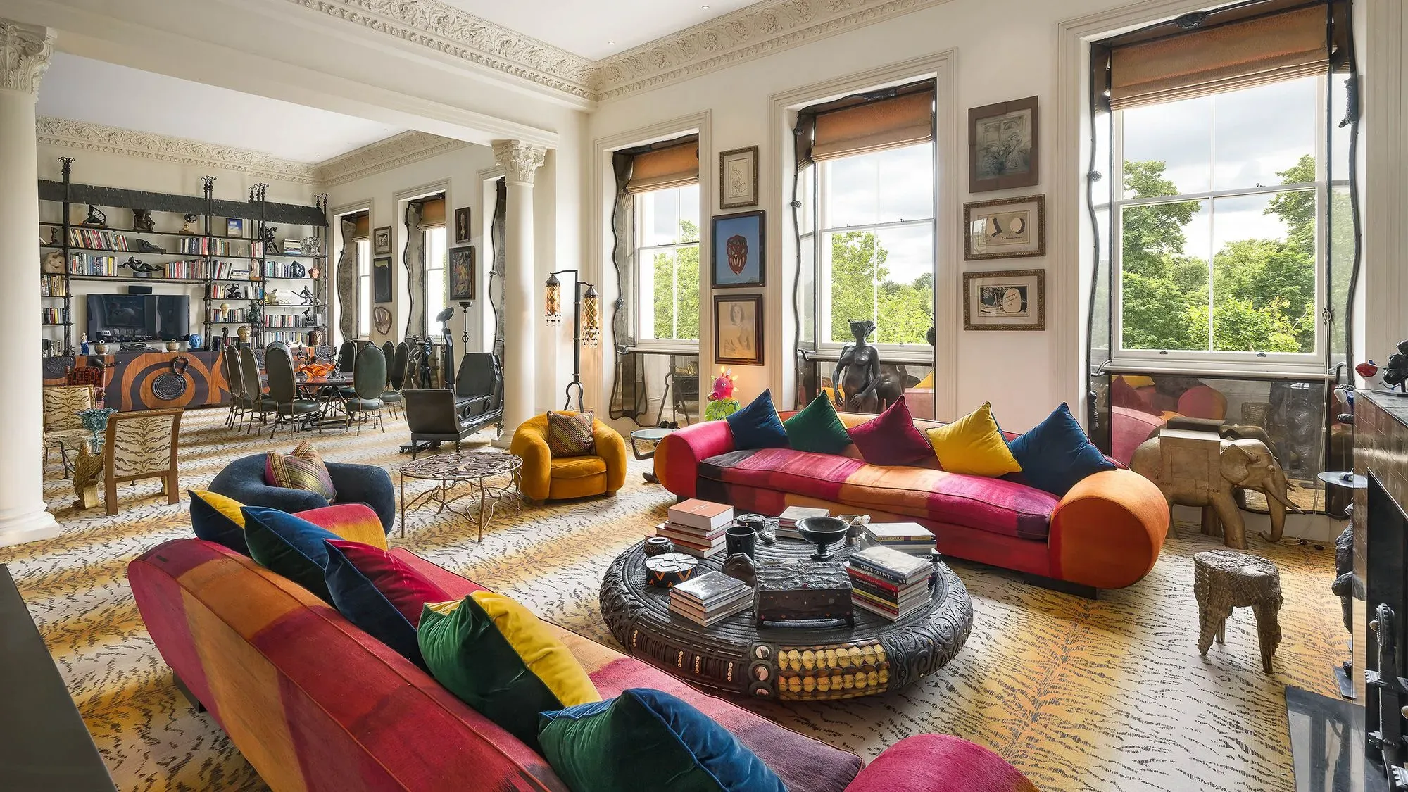 غرفة معيشة أنيقة ومليئة بالألوان، تحتوي على أرائك ملونة وطاولة قهوة فريدة، مع إطلالة على حديقة هايد بارك في لندن.