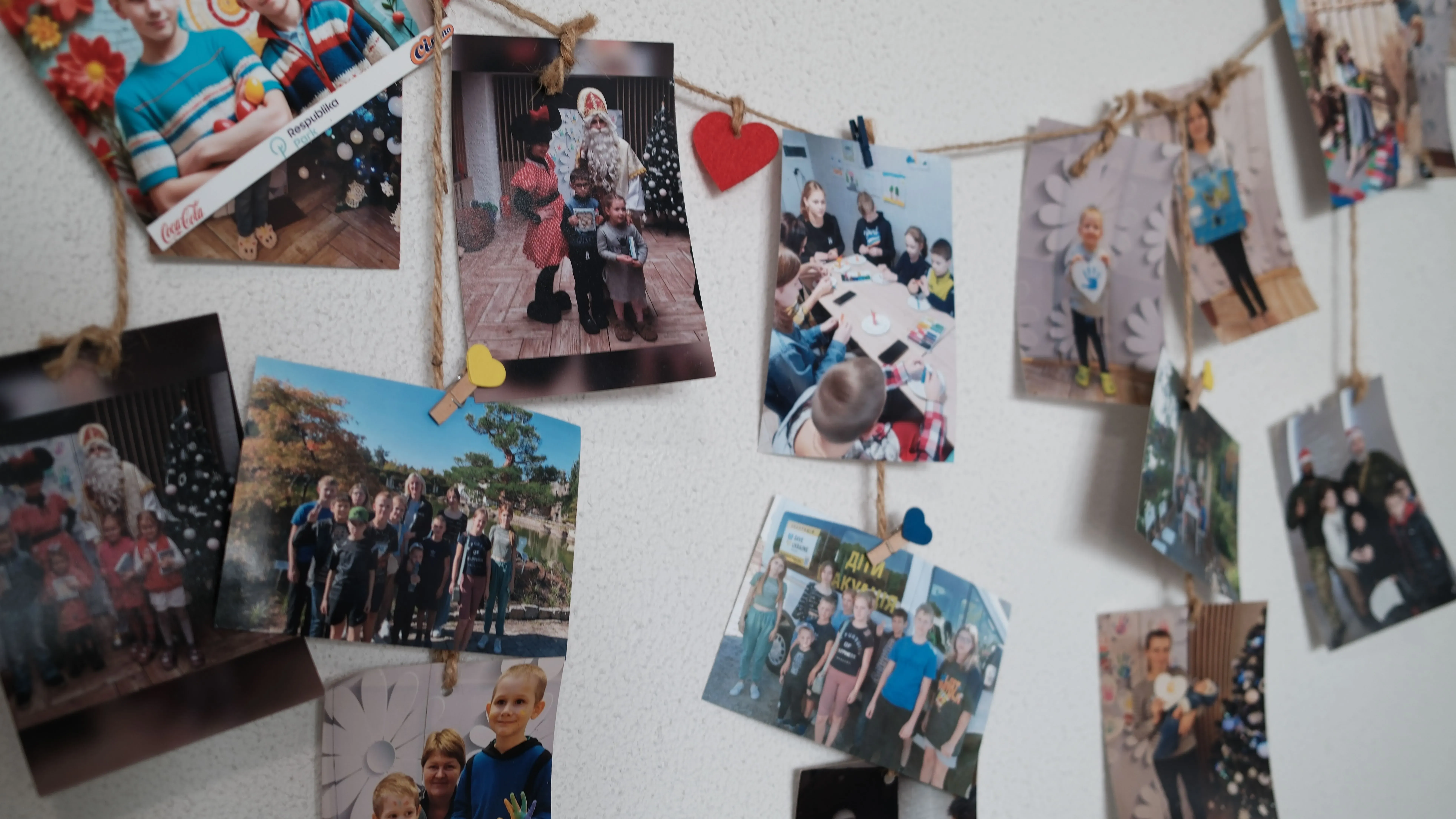 صور ملونة معلقة على حبل، تظهر أطفالًا ومناسبات سعيدة، تعكس حياة الأطفال الأوكرانيين الذين عادوا إلى وطنهم بعد التهجير.