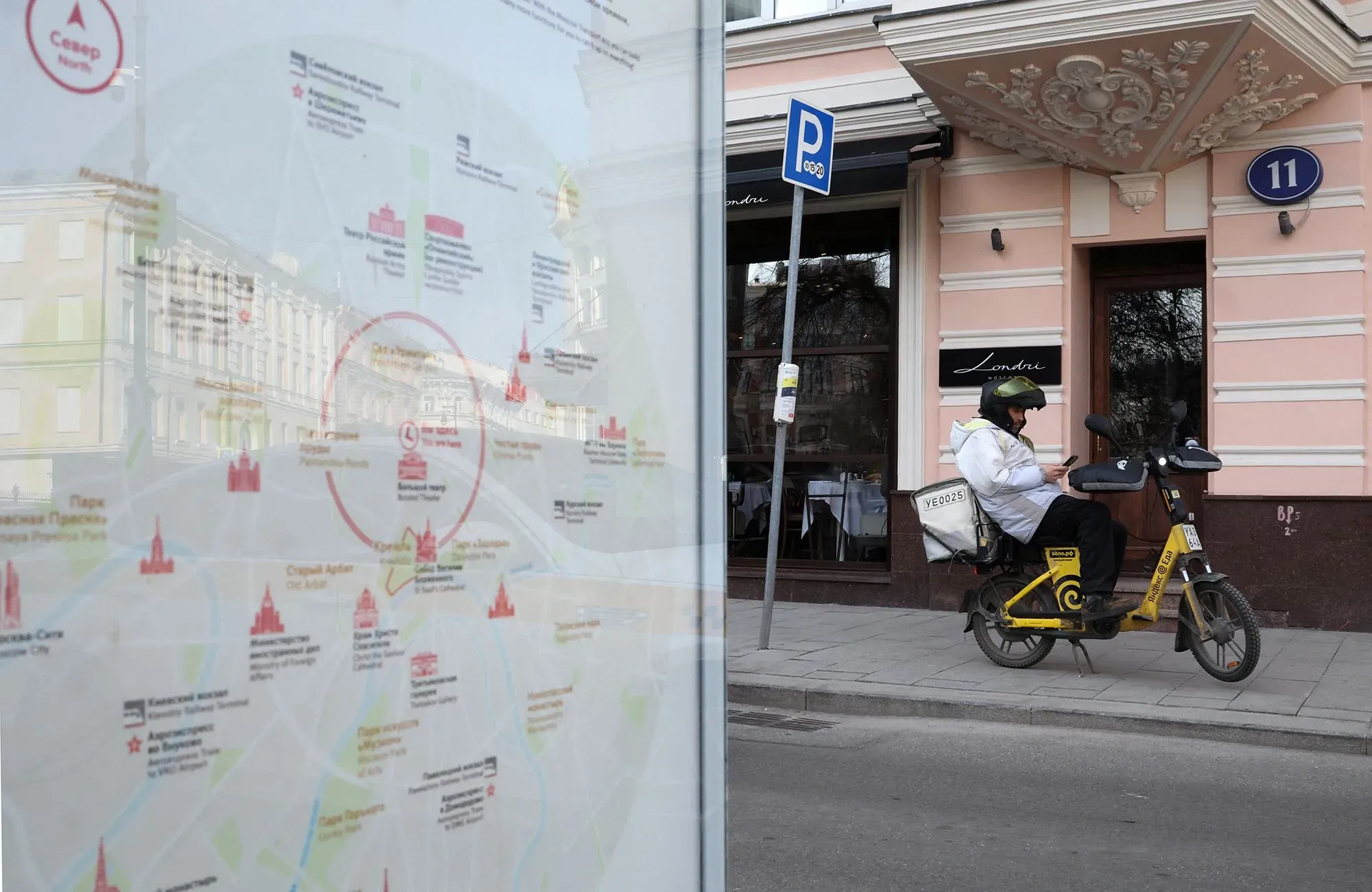 راكب دراجة كهربائية يجلس بجوار خريطة توضح معالم موسكو، مع مطعم في الخلفية، في سياق انقطاع خدمات الإنترنت في المدينة.