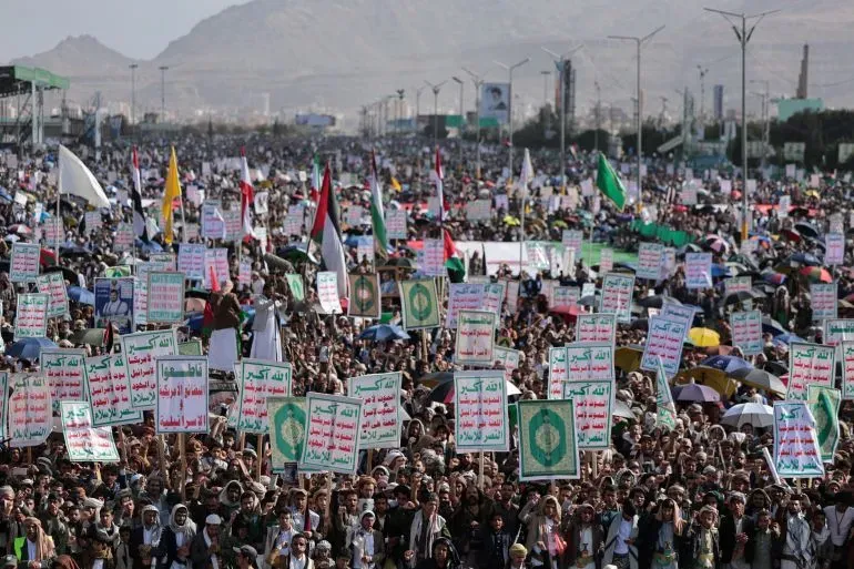 مظاهرة حاشدة في إيران، حيث يحمل المتظاهرون لافتات تعبر عن دعمهم للبنان، مع خلفية جبال. تعكس الصورة التوترات السياسية في المنطقة.