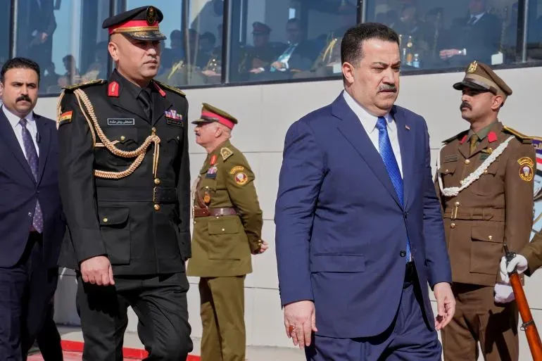 رئيس الوزراء العراقي محمد شياع السوداني يتقدم موكبًا رسميًا، محاطًا بضباط أمن، في سياق سياسي متوتر بعد الانتخابات.