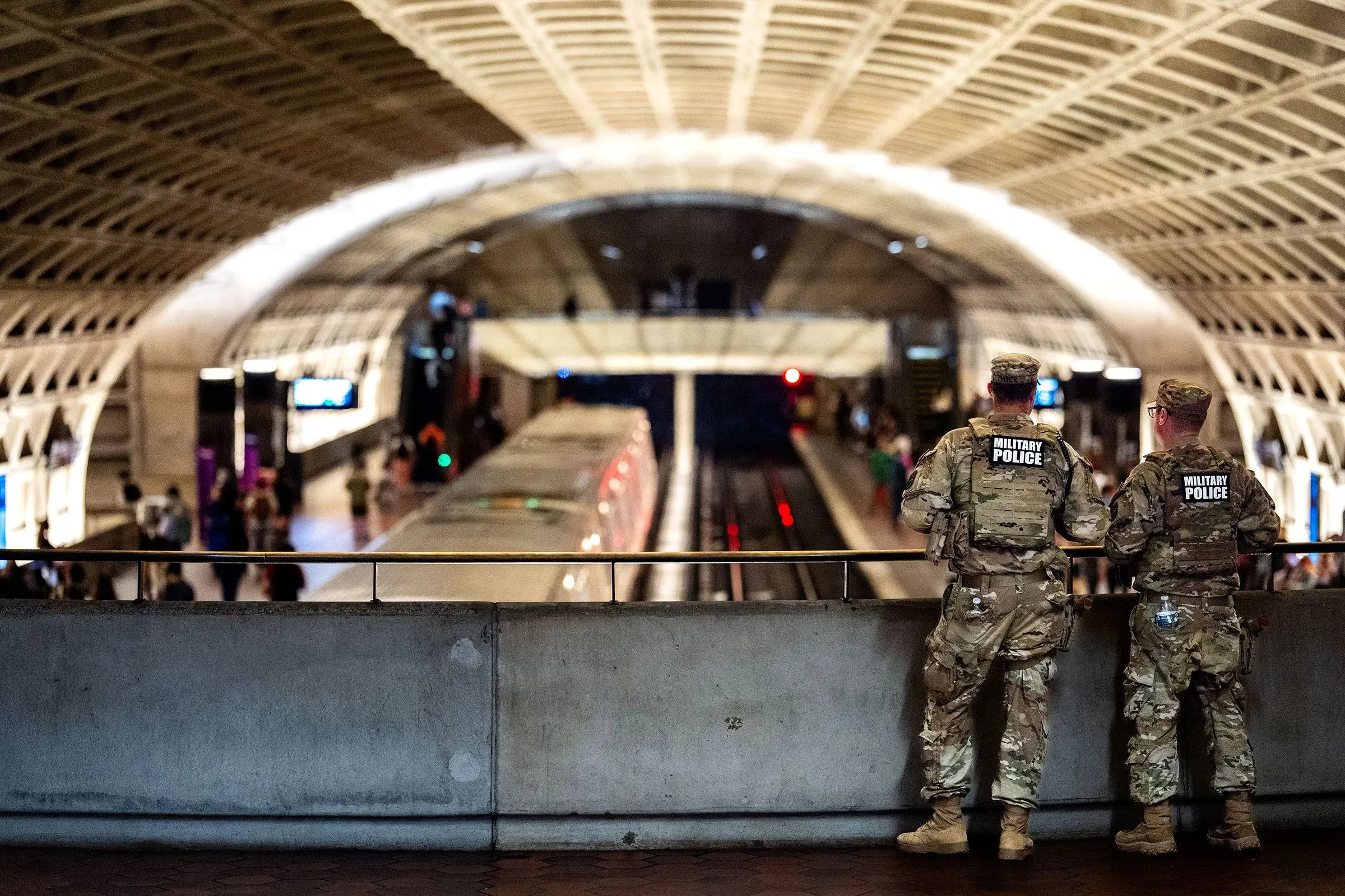 جنود من الشرطة العسكرية يقفون في محطة مترو أنفاق، يراقبون حركة الركاب، في سياق جهود مكافحة الجريمة.