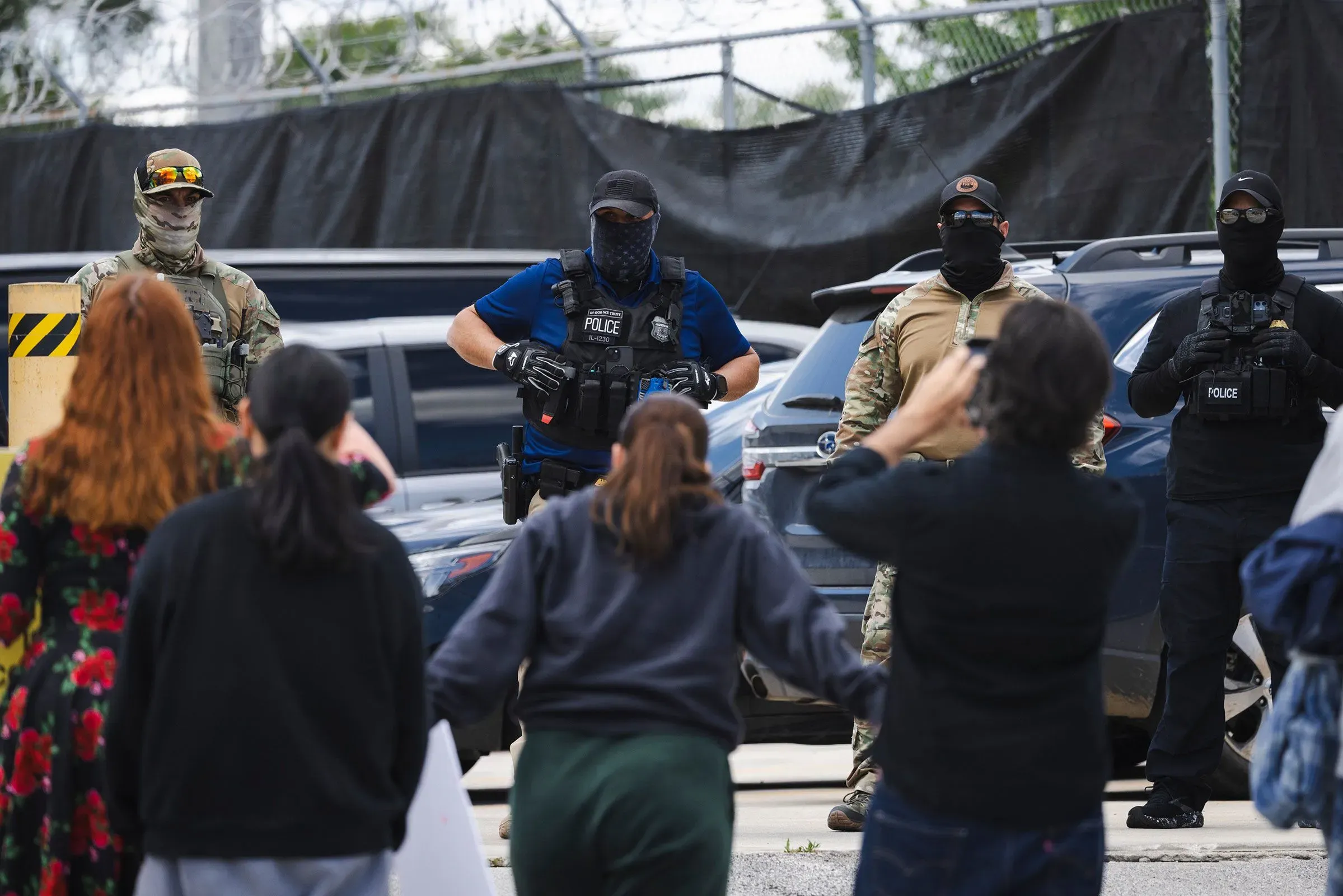 مجموعة من رجال الأمن يرتدون زيًا عسكريًا وأقنعة، يتواجدون أمام مجموعة من المتظاهرين في شيكاغو.