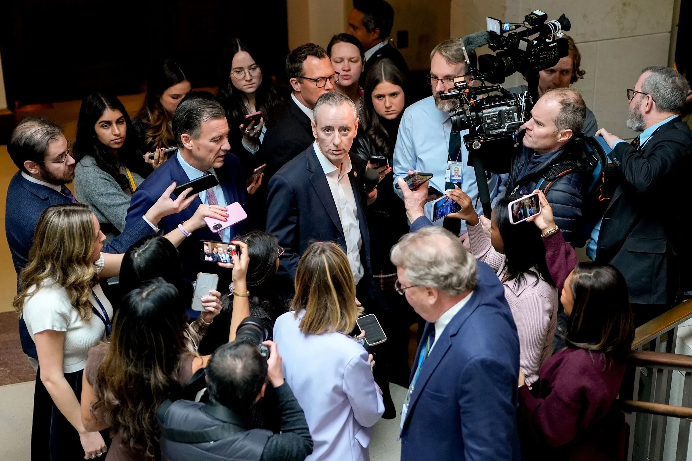 مجموعة من الصحفيين والمراسلين يحيطون بشخصية سياسية تتحدث في مكان عام، مع وجود كاميرات وهواتف تسجل الحدث.