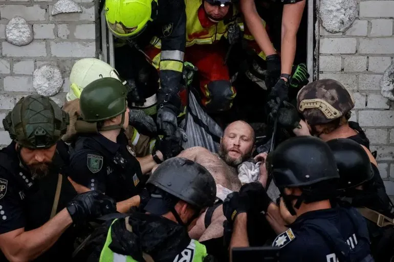 إنقاذ رجل مصاب من مبنى مدمر، حيث يعمل رجال الإطفاء والشرطة معًا في عملية إنقاذ خلال النزاع في أوكرانيا.