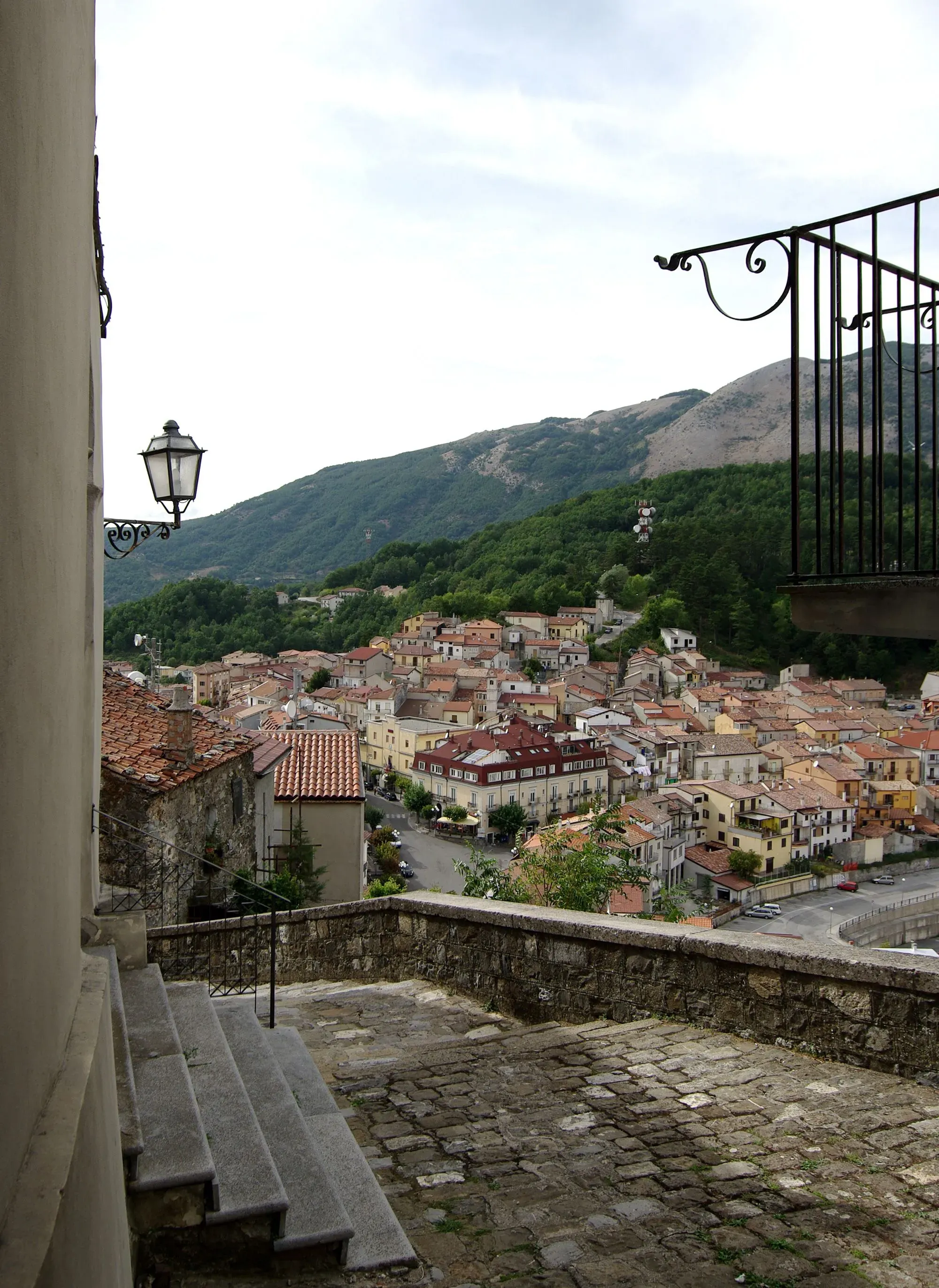 منظر بانورامي لقرية لاترونيكو الإيطالية، يظهر المنازل الملونة المحاطة بالجبال، مع درج حجري يؤدي إلى الشرفة.