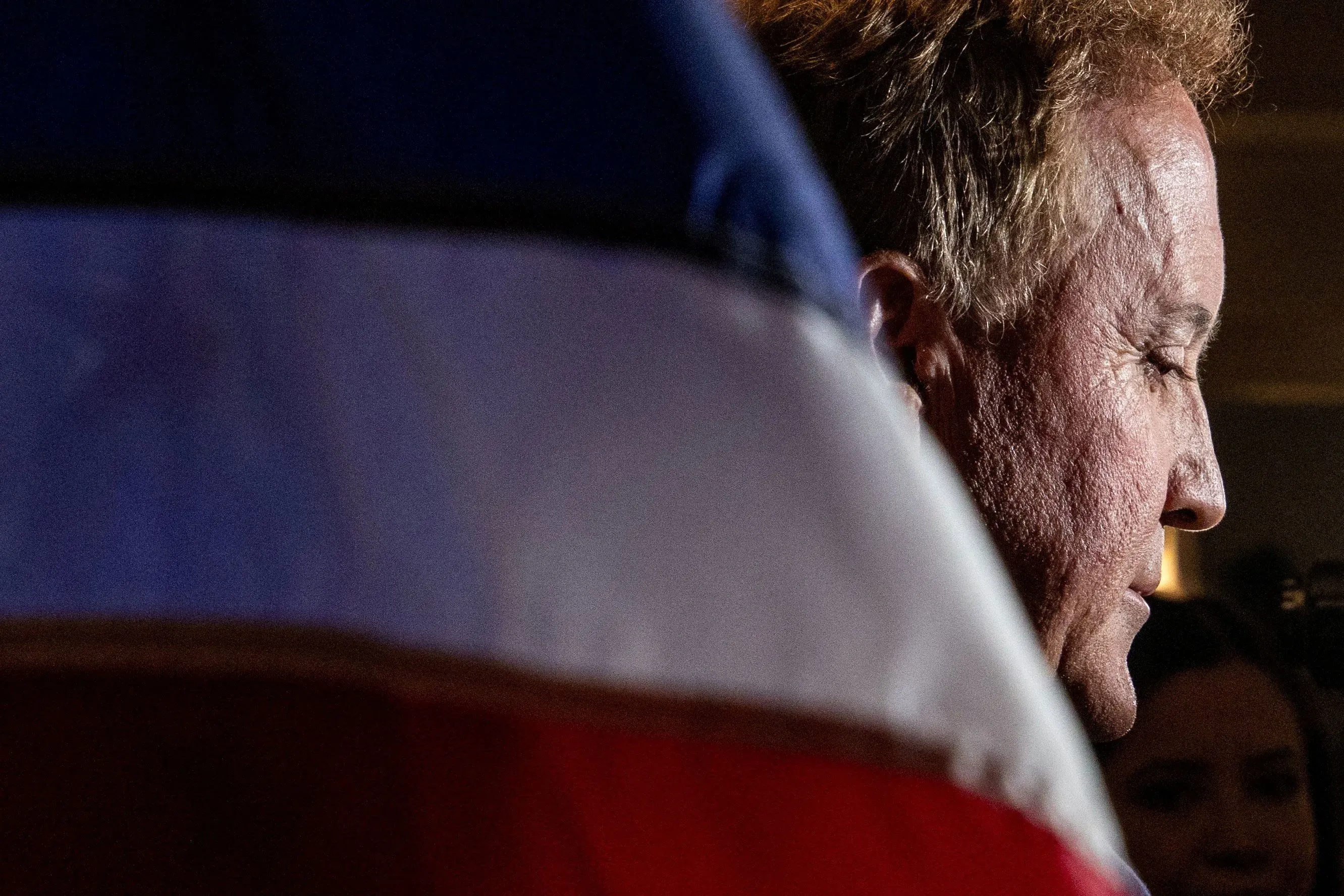 صورة تظهر جانب وجه سياسي يقف أمام علم تكساس، تعكس التوترات السياسية المتعلقة بالخطاب المعادي للإسلام في الانتخابات.