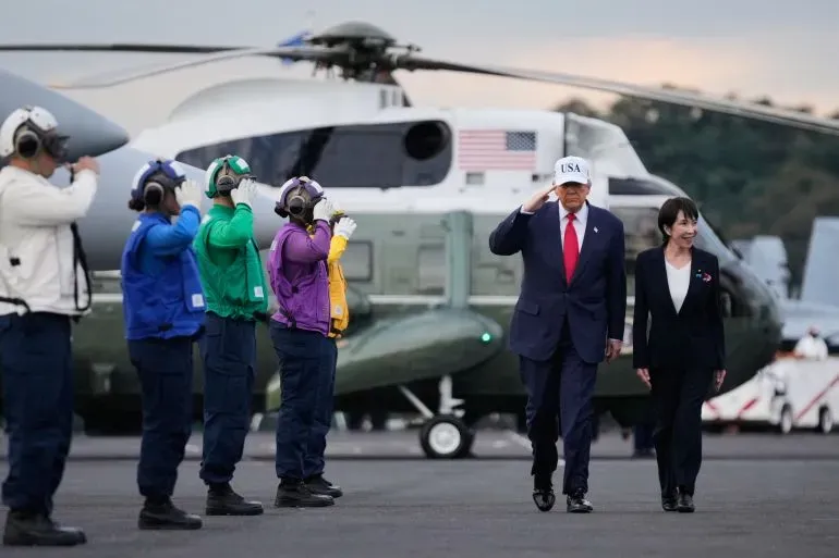 زيارة رسمية في اليابان، حيث يظهر شخص يرتدي قبعة مكتوب عليها "USA" بينما يقوم أفراد من القوات العسكرية بتحية رسمية.