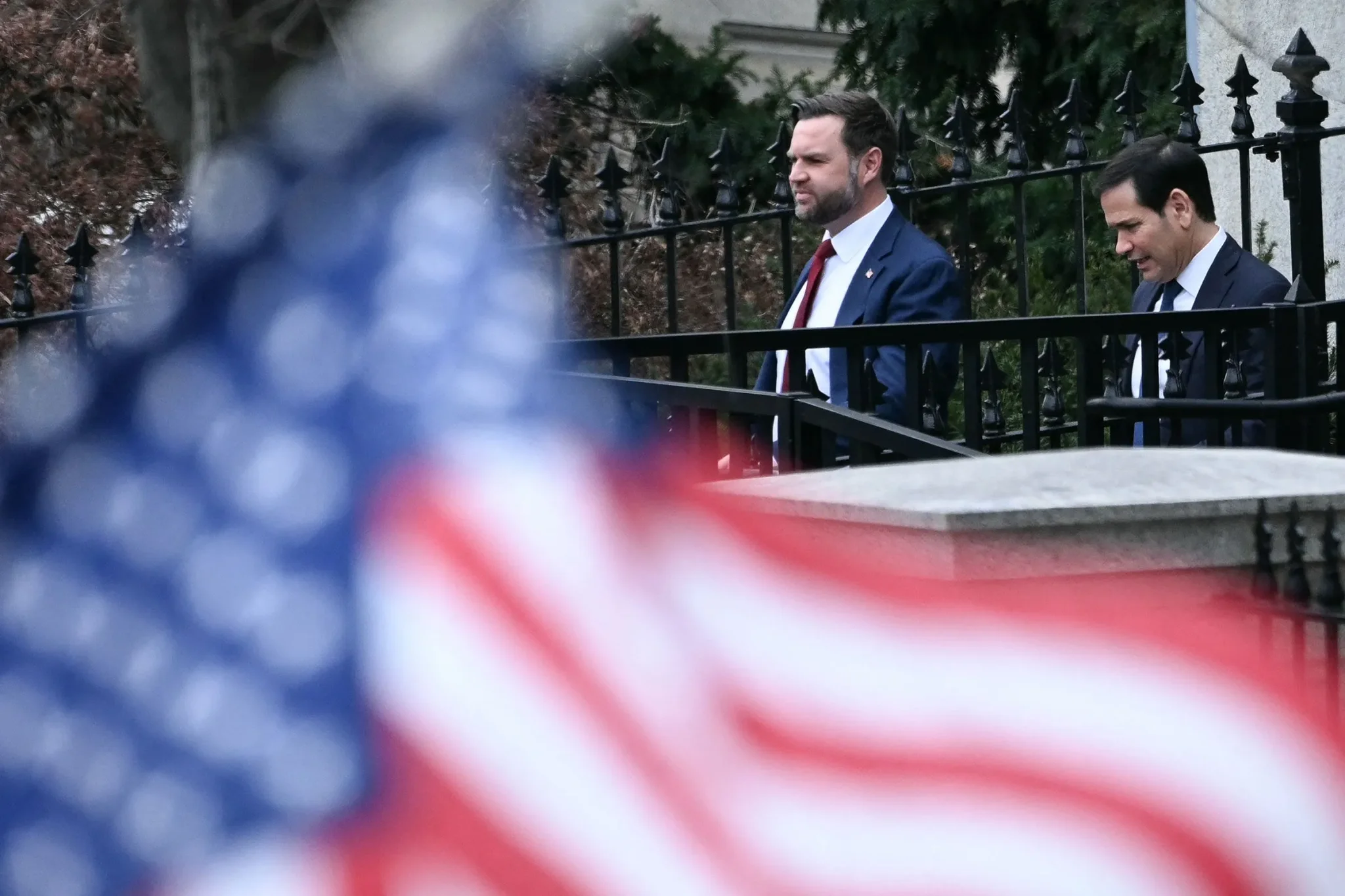 نائب الرئيس الجمهوري JD Vance يمشي بجانب عضو آخر للحزب خلف علم أمريكي، مع التركيز على دوره في إعادة صياغة رسالة الحزب استعدادًا لانتخابات 2028.