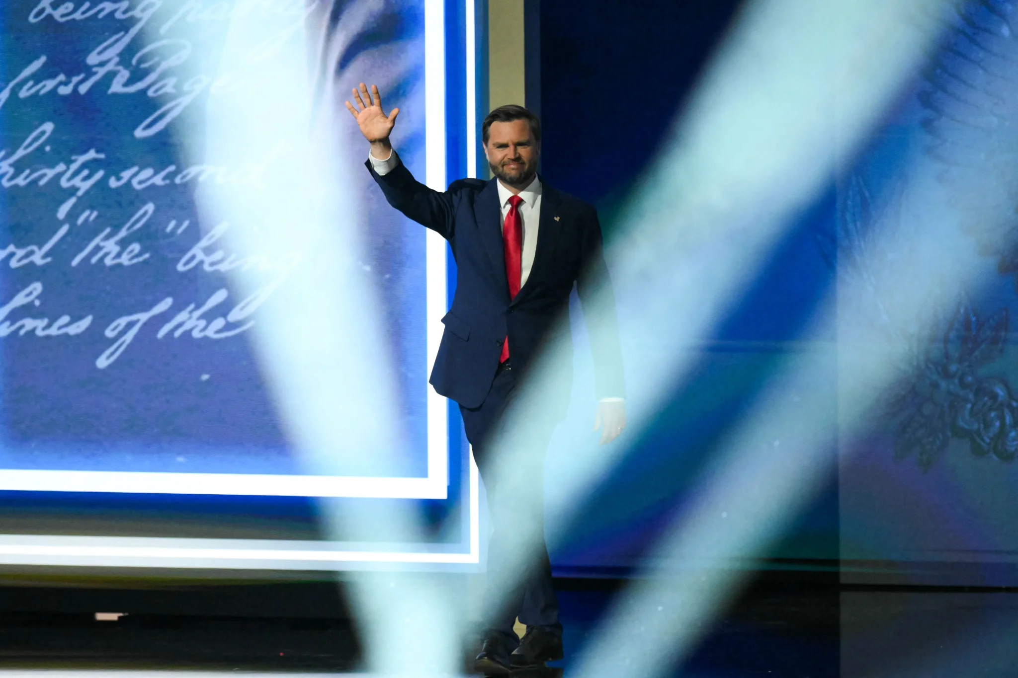 نائب الرئيس الجمهوري JD Vance يلوح بيده على المسرح خلال مؤتمر الحزب في دالاس، مع تسليط أضواء قوية تعكس دوره في إعادة صياغة رسالة الحزب الانتخابية.
