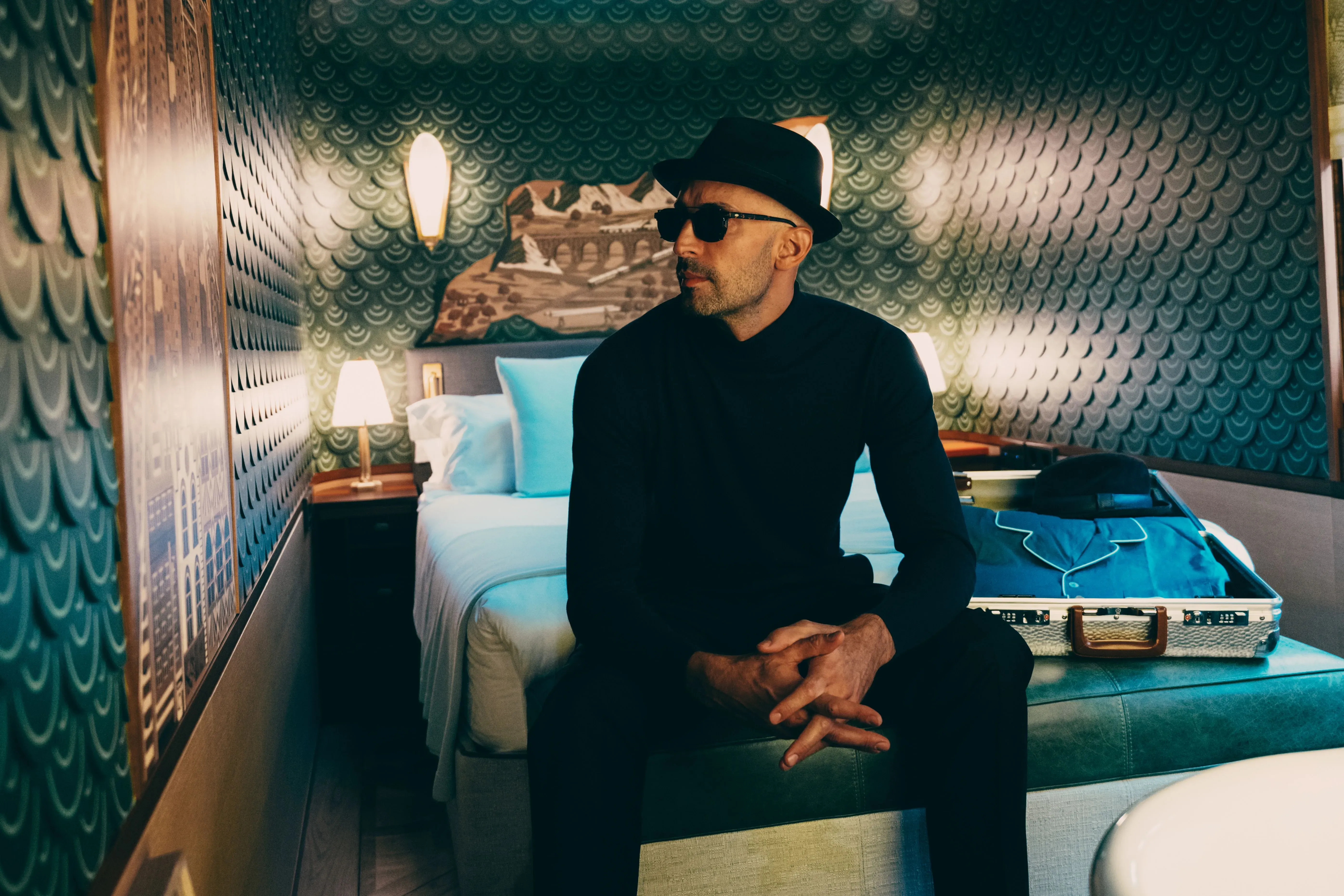 فنان الشارع جي آر يجلس في عربة قطار مصممة حديثًا، محاطة بتفاصيل فاخرة، تعكس إبداعه في تصميم "L'Observatoire".