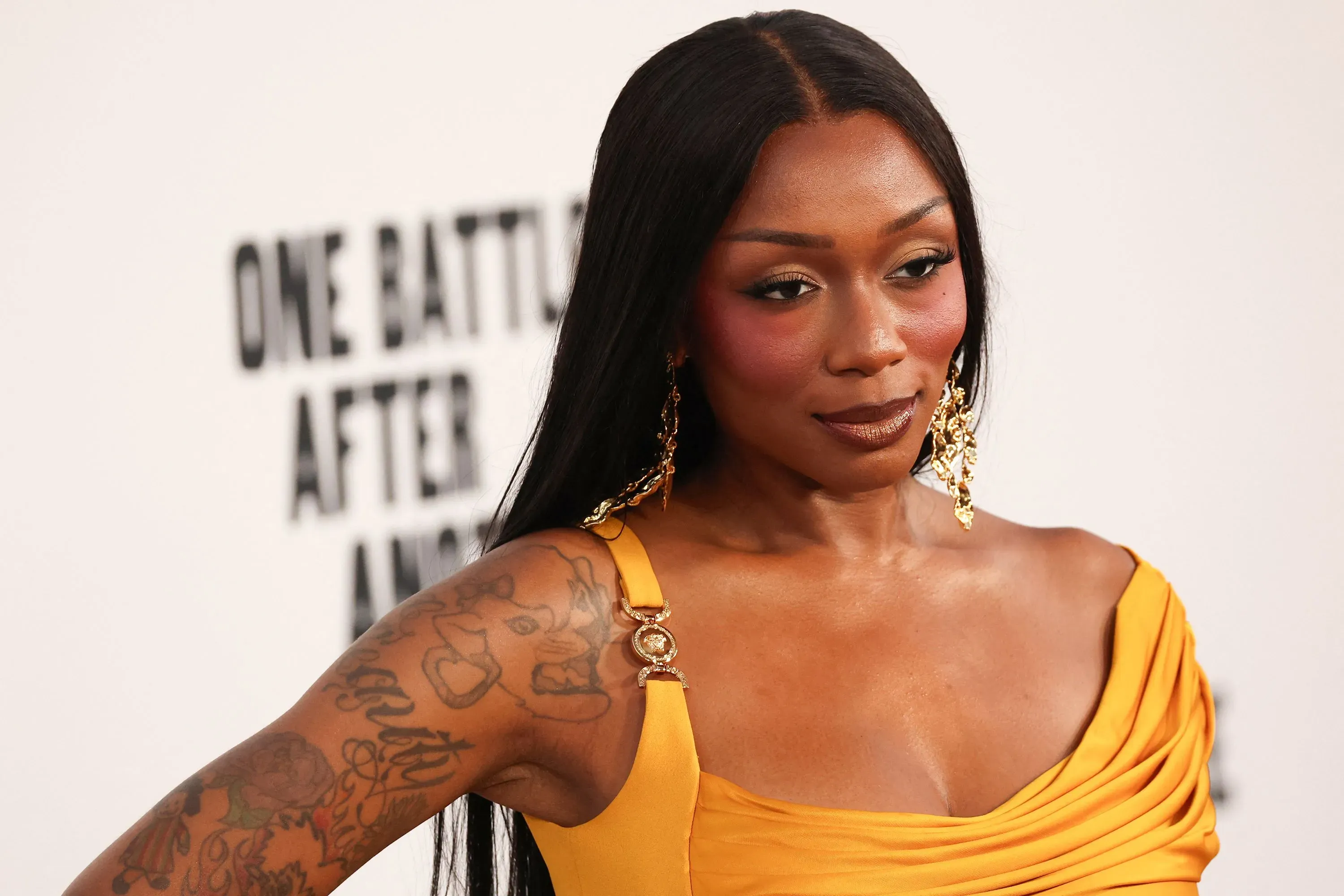 مغنية الراب جانجل بوسي ترتدي فستانًا أصفر في عرض فيلم "معركة تلو الأخرى"، تعكس إطلالتها الثقة والإبداع الفني.