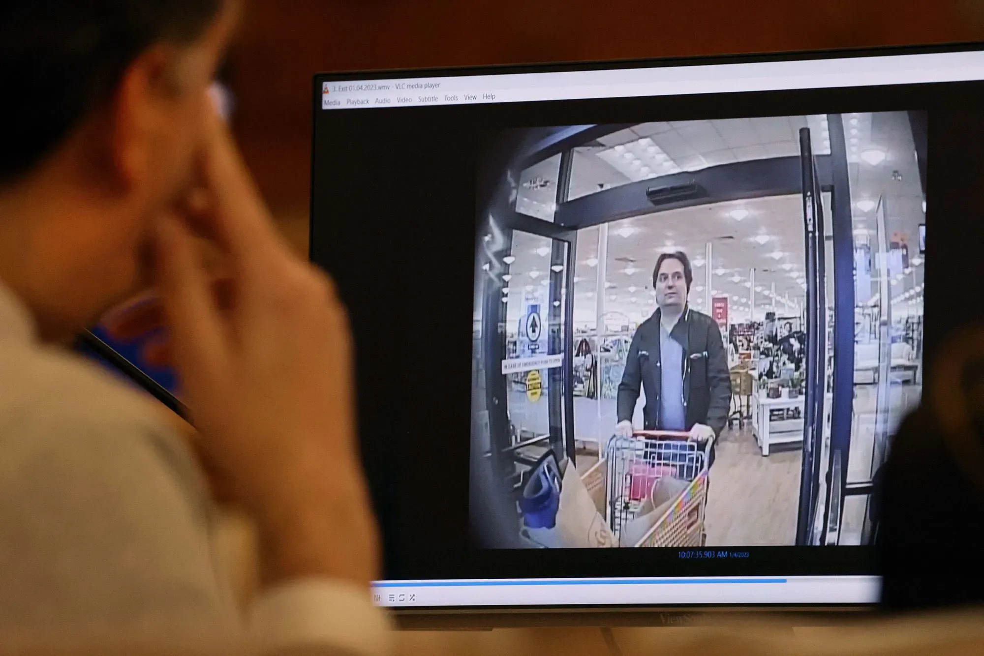 صورة تظهر براين والش وهو يتسوق في متجر، مع التركيز على تفاصيل وجهه وتعبيره أثناء مشاهدته لقطات كاميرا المراقبة.