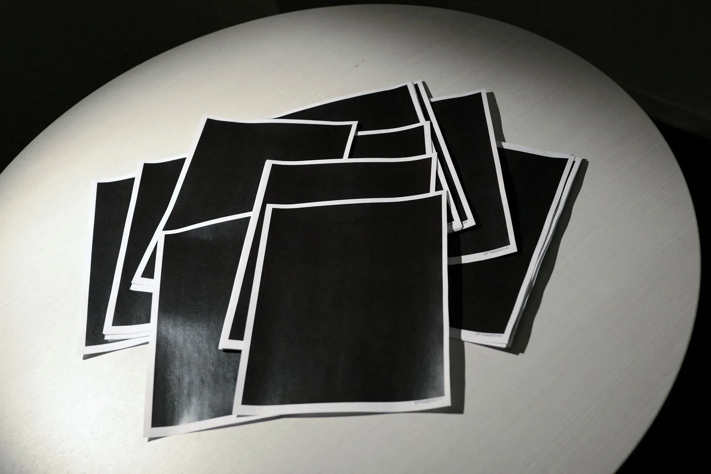 مجموعة من الأوراق المطبوعة باللون الأسود، تشير إلى المعلومات المحجوبة عن ضحايا جيفري إبشتاين، مما يعكس غياب الشفافية في الوثائق القانونية.