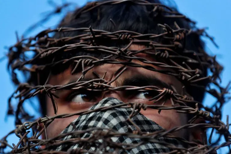 شاب محاط بسياج شائك، يعكس معاناة كشمير تحت الاحتلال، ويظهر آثار القمع العسكري والاحتجاجات.