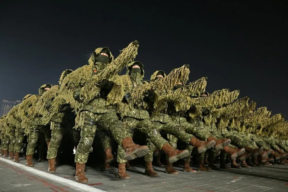 جنود كوريون شماليون يرتدون ملابس تمويهية ويستعرضون أسلحة خلال عرض عسكري ليلي في بيونغ يانغ، مع التركيز على الانضباط والقوة العسكرية.