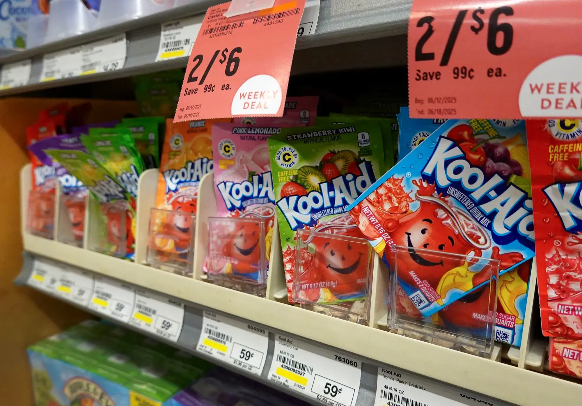 أرفف المتجر تعرض عبوات متنوعة من مشروب كول آيد، مع ملصق يوضح عرضًا خاصًا. تشير العبوات إلى تجديد العلامة التجارية.