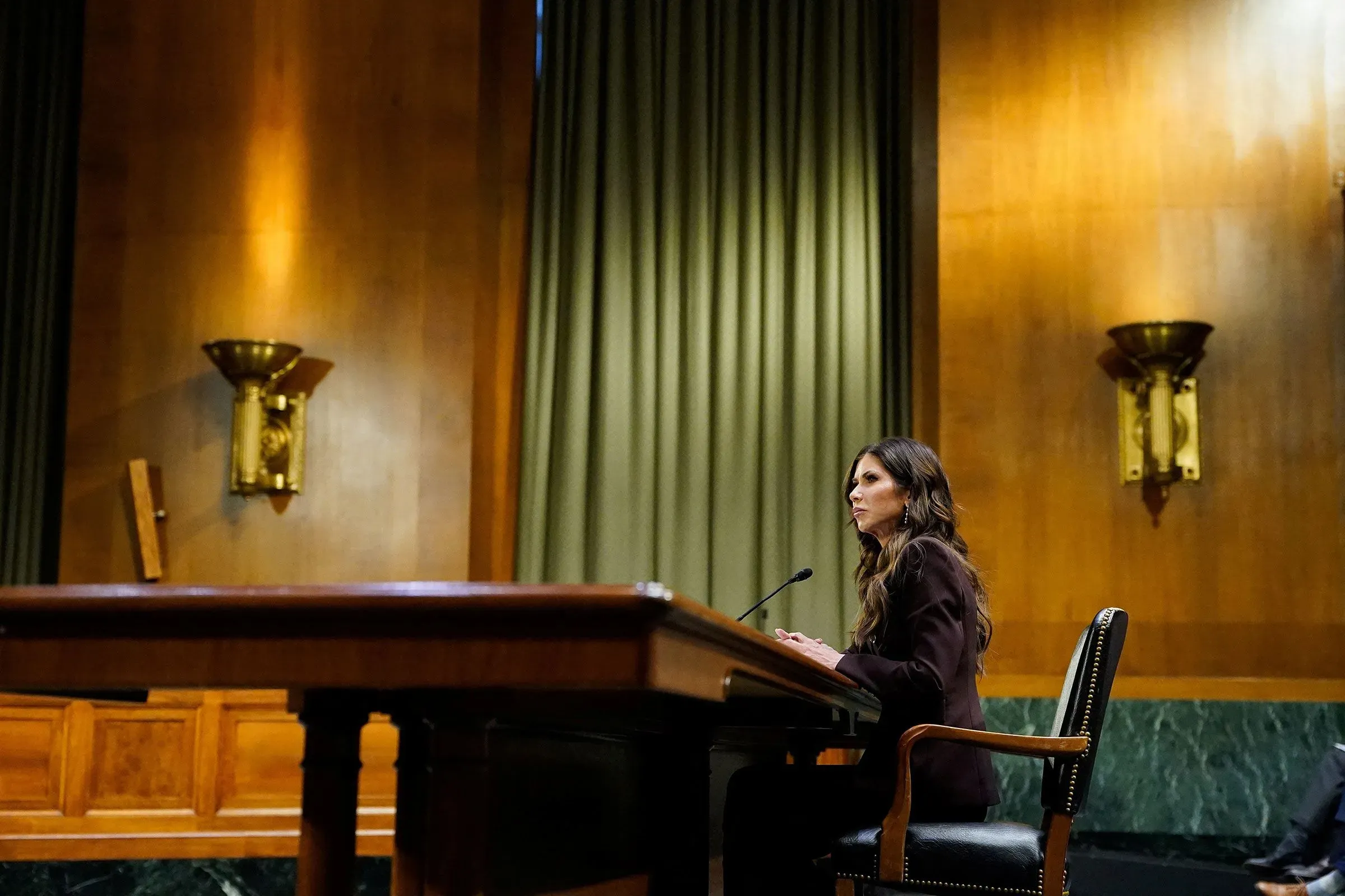 كريستي نويم تتحدث أمام اللجنة في مبنى حكومي، مع التركيز على قضايا الأمن الوطني وإنفاذ قوانين الهجرة، وسط أجواء رسمية.