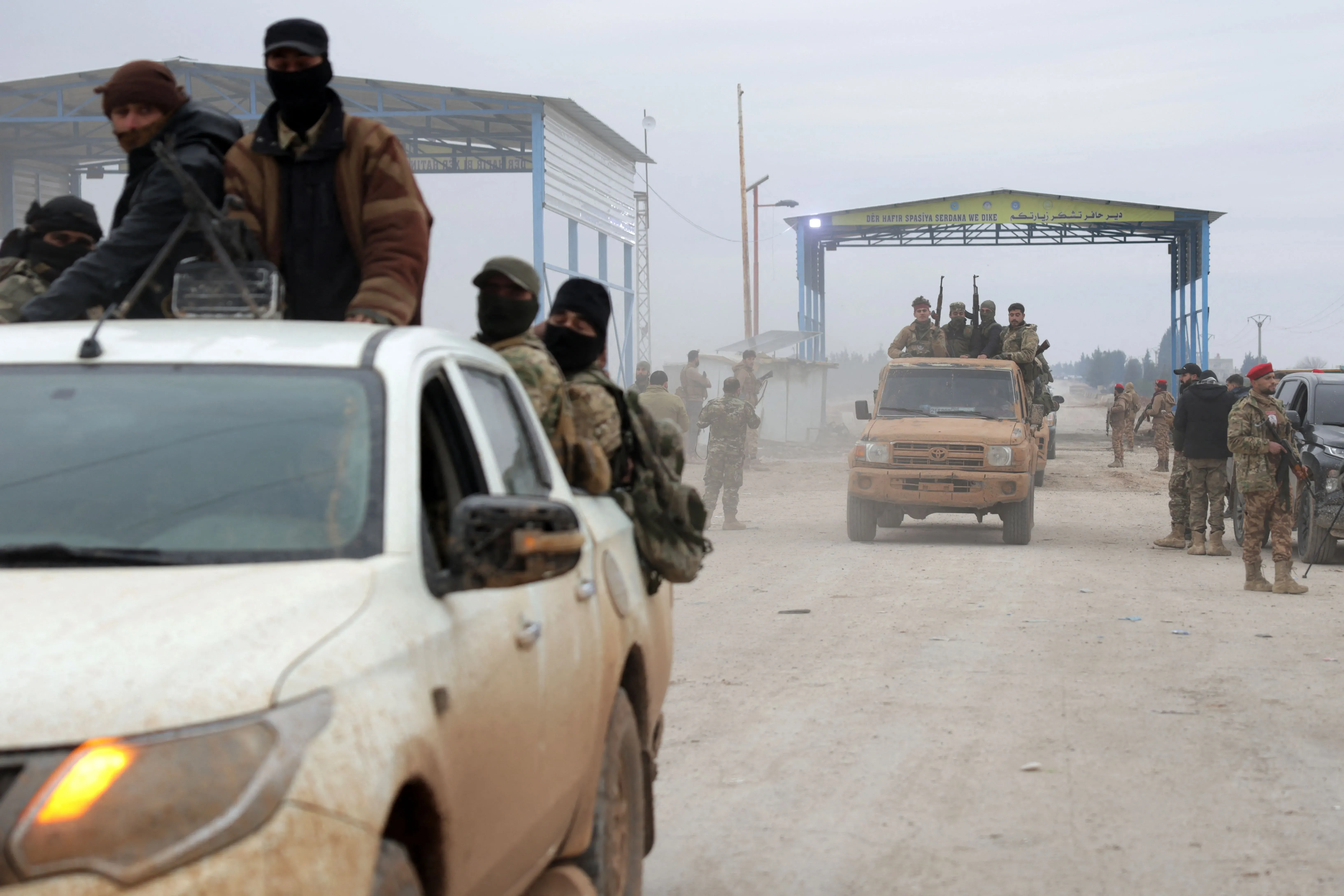 تظهر الصورة قوات سورية ديمقراطية تتواجد في منطقة عسكرية، مع مركبات عسكرية ووجود مسلحين، في سياق انسحابهم من شرق حلب.