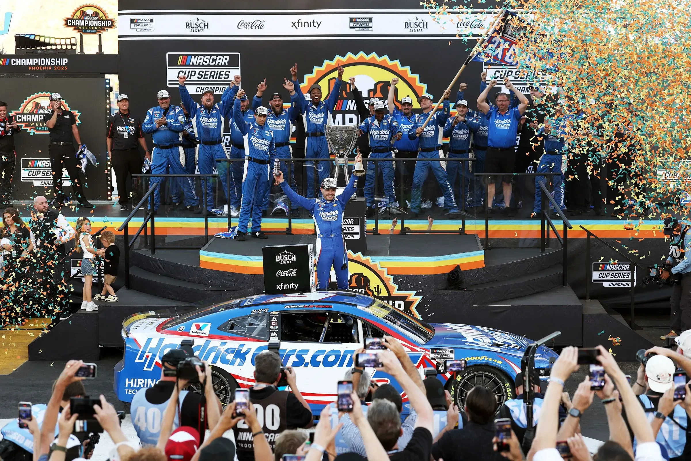 فوز كايل لارسون ببطولة كأس ناسكار 2025 في حلبة فينيكس ريسواي، مع احتفالات فريقه وتوزيع الشوكولاتة.