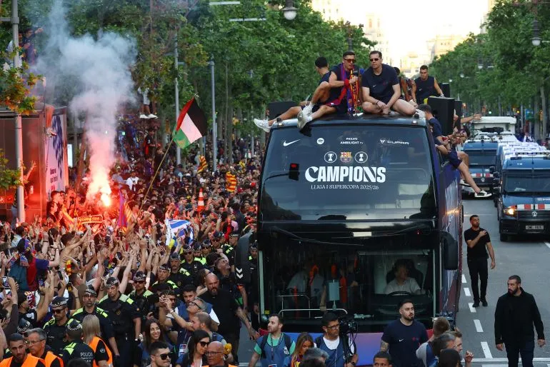 لاعب برشلونة الشاب لامين يامال يرفع العلم الفلسطيني وسط حشود من المشجعين خلال احتفال الفريق بلقب الدوري الإسباني في برشلونة.