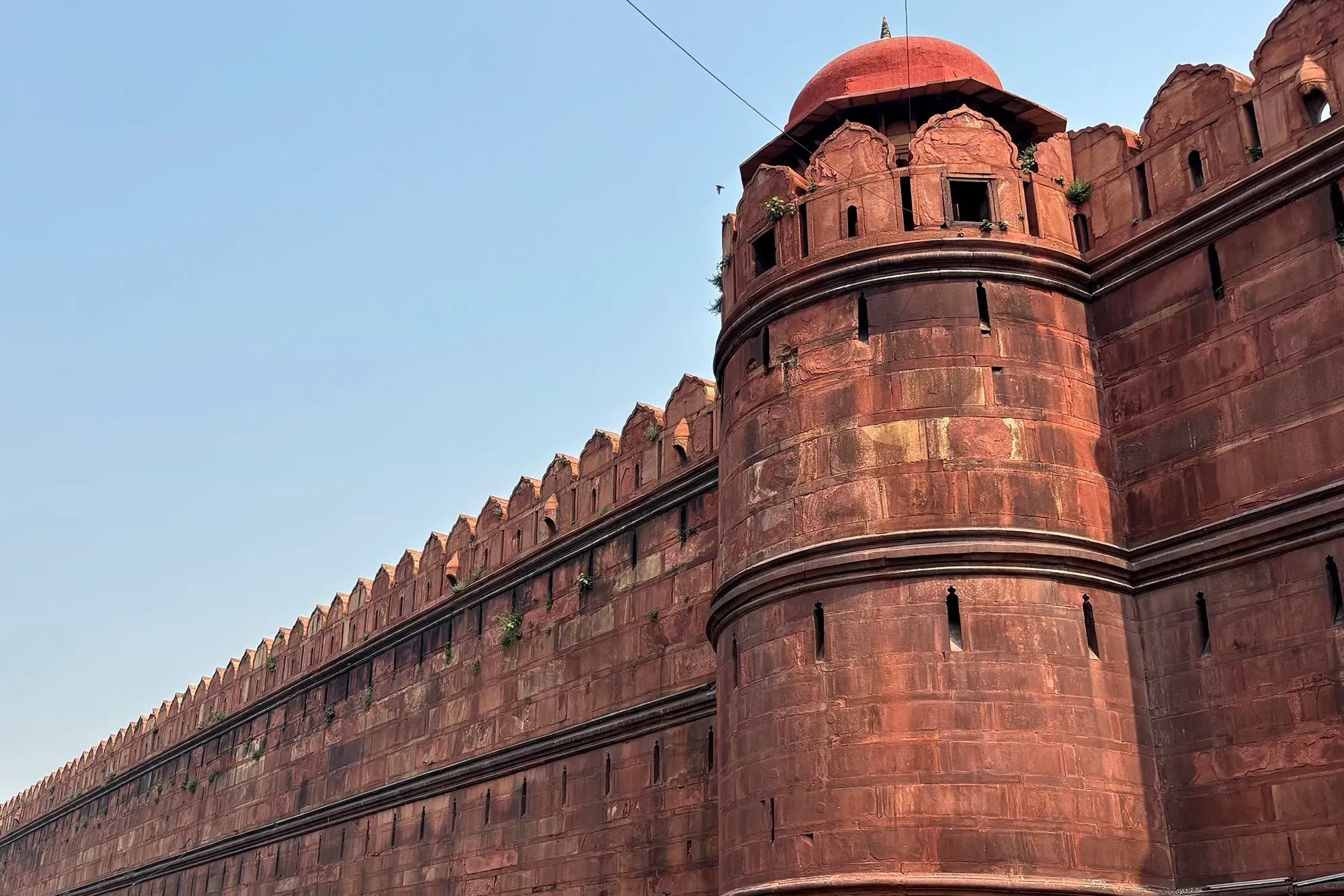 قلعة حمراء في نيودلهي، تظهر الجدران الخارجية المتهالكة والأقواس المعمارية، تعكس تأثير التلوث على المعالم التاريخية.