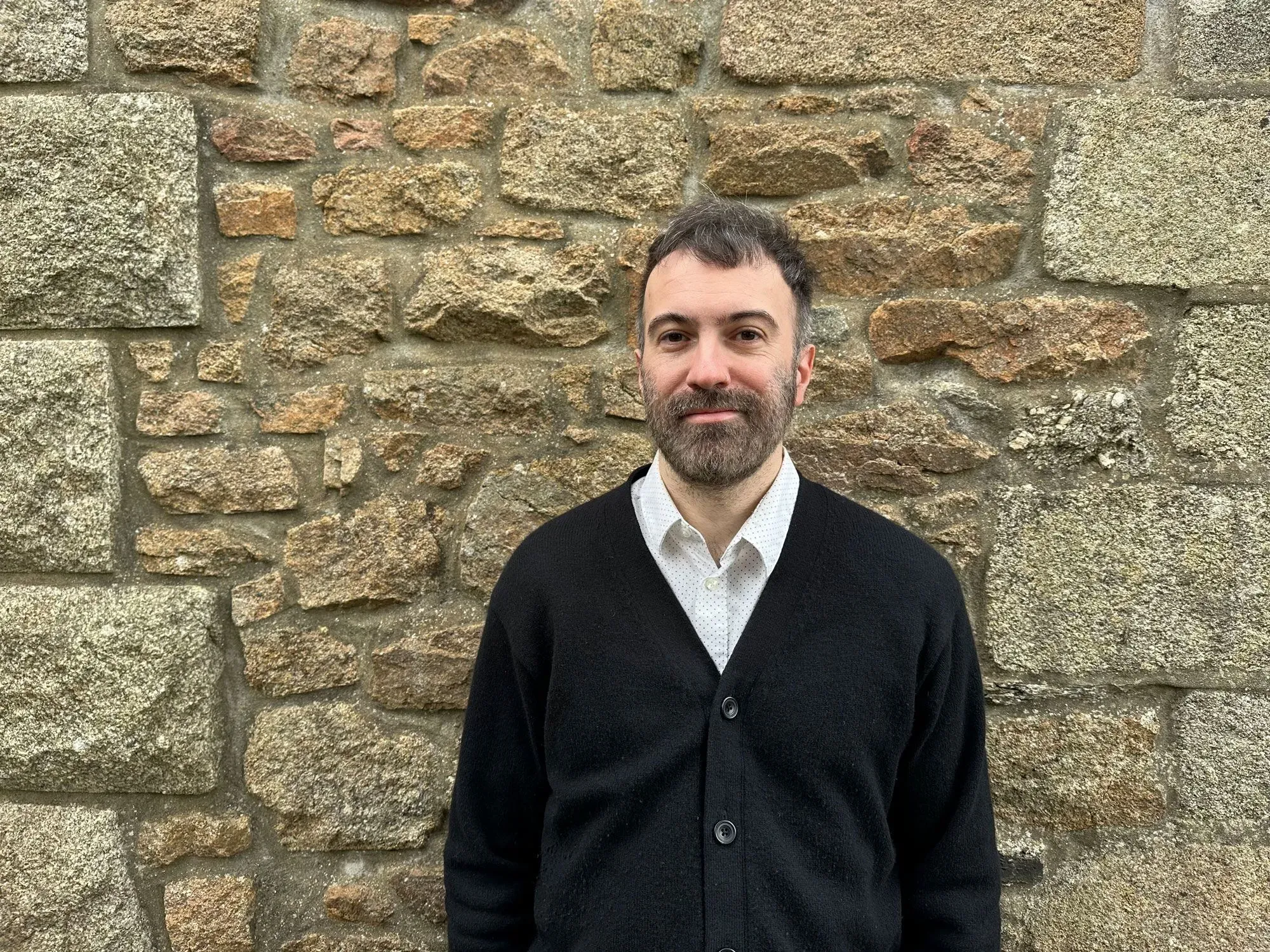 تيموثي ماكيون، مترجم للغة الأيرلندية، يقف أمام جدار حجري، معبرًا عن القلق من تأثير الذكاء الاصطناعي على مهنته.