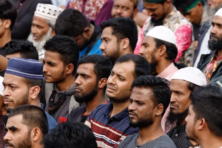 جموع من الرجال في دكا، يعبرون عن الحزن والتأمل خلال جنازة شريف عثمان هادي، وسط أجواء من التأثر والحداد.