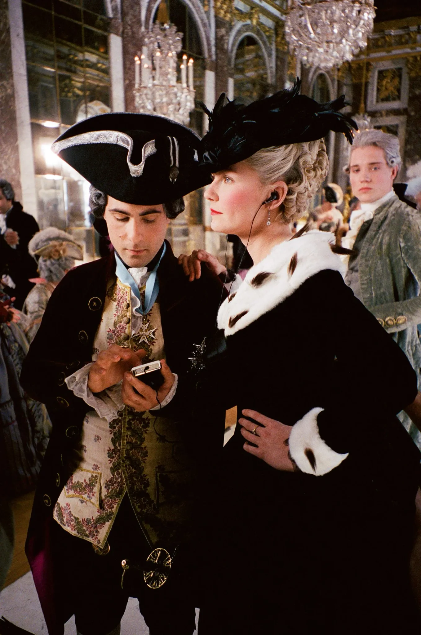 مشهد من فيلم "Marie Antoinette" لسوفيا كوبولا يظهر ممثلين يرتدون أزياء تاريخية باروكية داخل قصر فرساي، يعكس أجواء التصوير والديكور الفخم للفيلم.