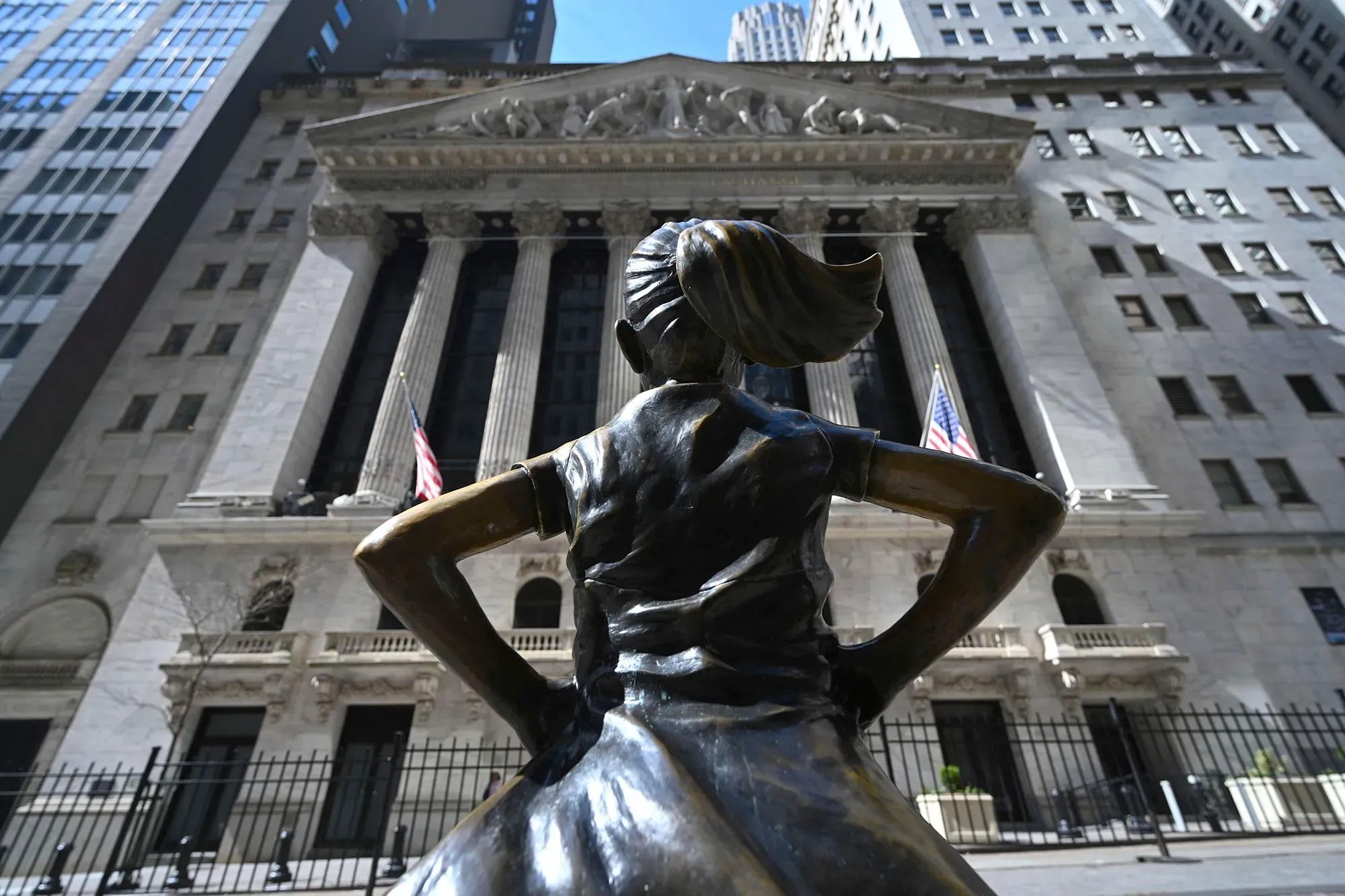 تمثال برونزي لفتاة صغيرة تراقب مبنى بورصة نيويورك، مما يرمز إلى القوة والثقة في الأسواق المالية.