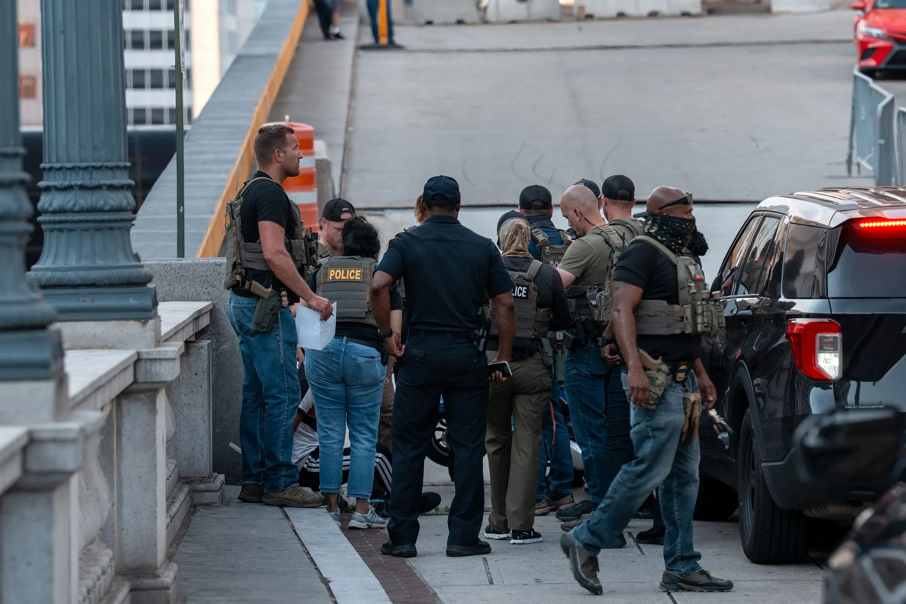 اعتقال مهاجرة كولومبية في لوس أنجلوس من قبل ضباط ملثمين، مع وجود سيارات الشرطة والمارة في الخلفية، يعكس تصاعد عمليات إنفاذ قوانين الهجرة.